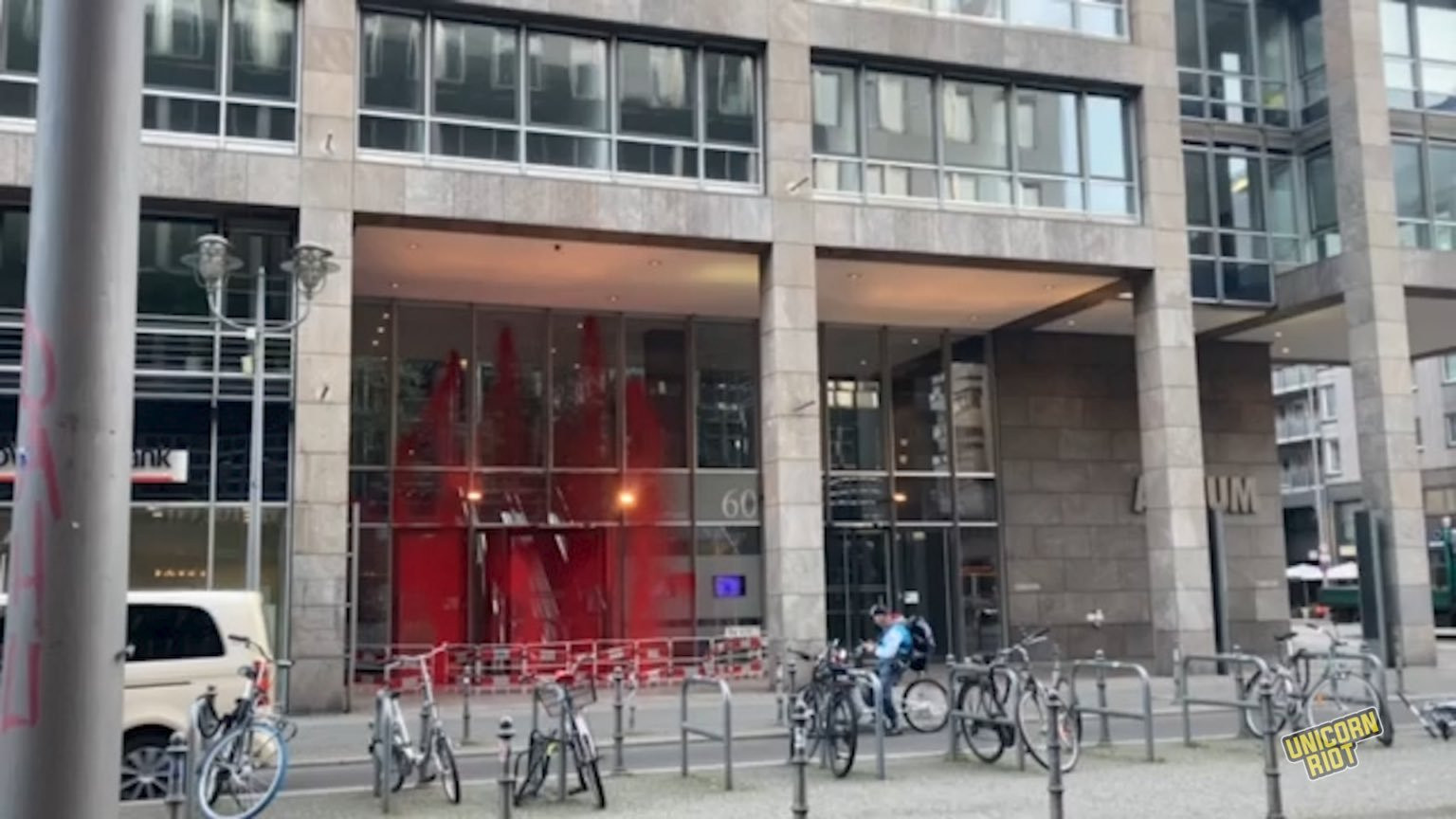 Red paint seen on the entrance to Friedrichstraße 60 in downtown Berlin during the daytime on Monday, March 18, 2024. Large plate glass windows at the ground floor entrance to a large office tower are seen covered in red paint behind bikes locked to individual bike racks.