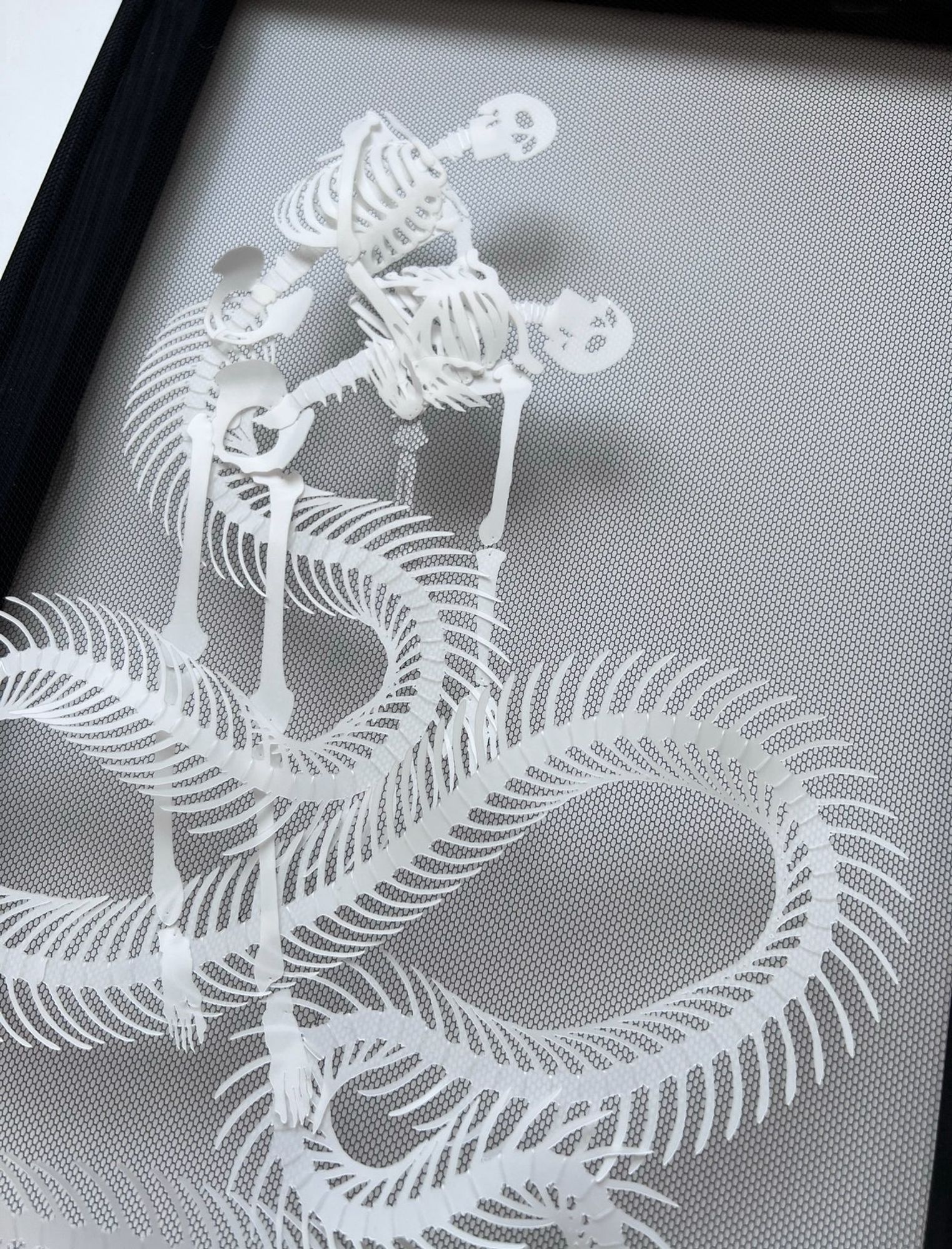 Detail of mermaid skeleton with very long sinuous tail weaving around a swooning human skeleton