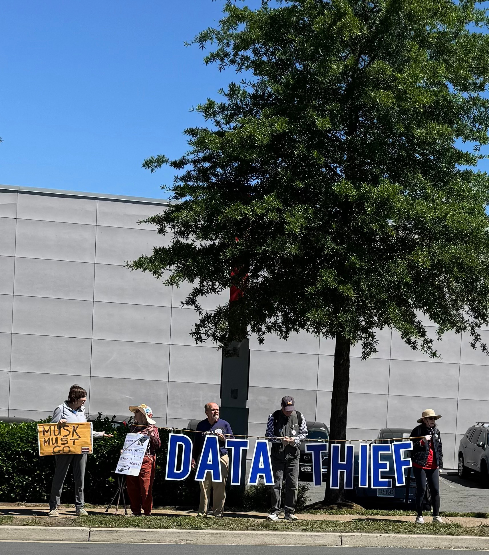 Activists hold sign DATA THIEF at Tesla