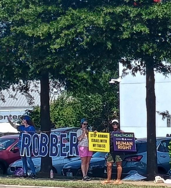 Activists hold sign ROBBER at Tesla