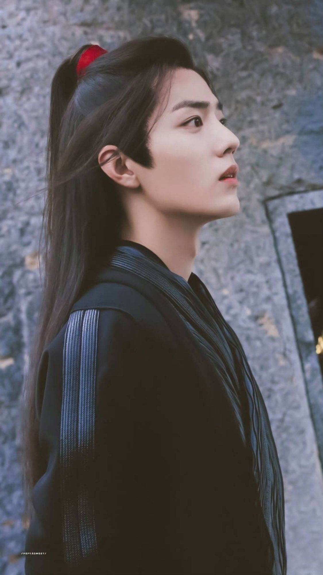 Xiao Zhan behind the scenes of the Untamed. He's wearing black robes and looks slightly surprised.