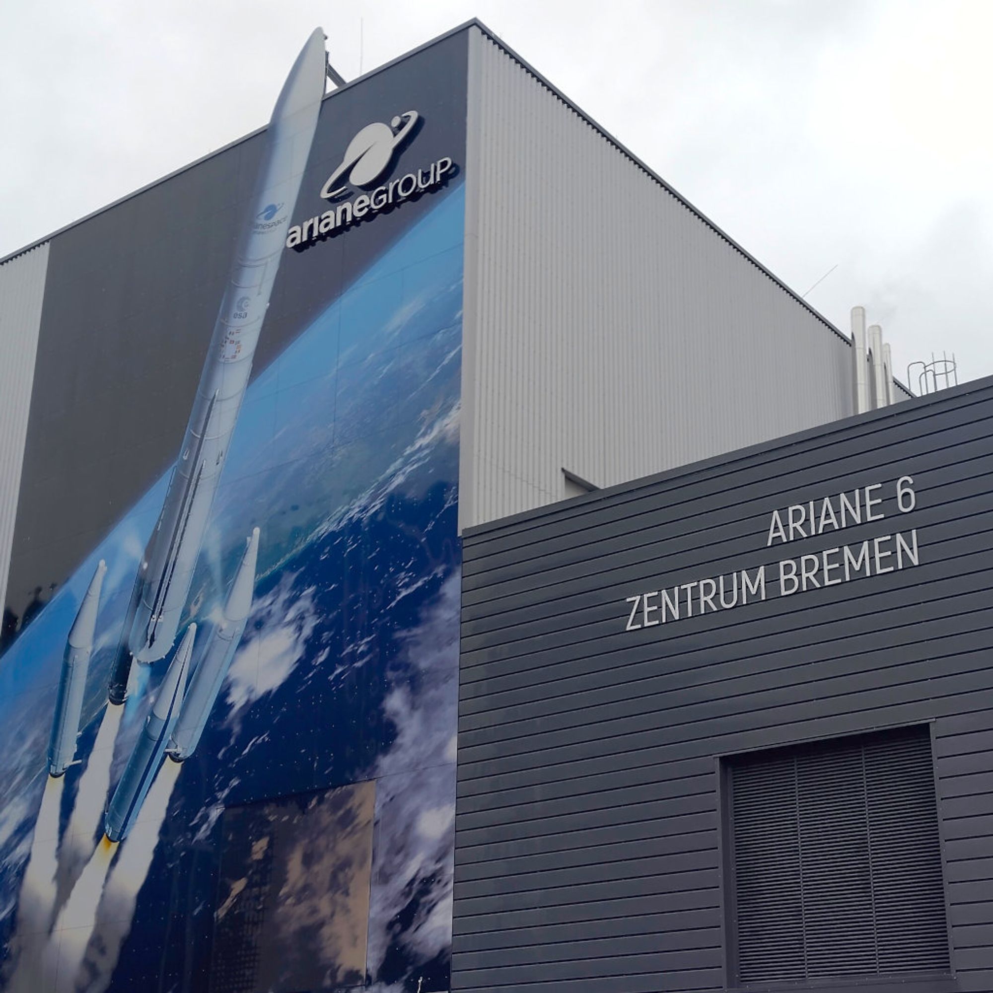 Produktionsgebäude von ArianeGroup in Bremen mit Schriftzug "Fassade des Ariane 6 Zentrum" und einer Darstellung einer Ariane 64 bei Abtrennung der Booster