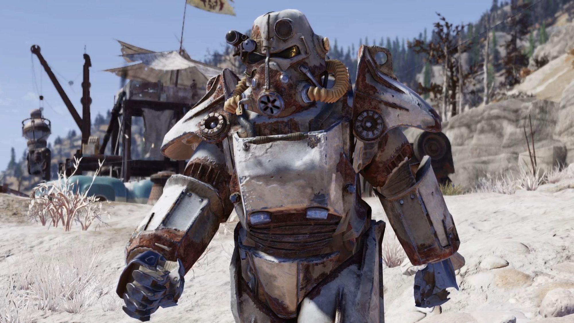 Screenshot from the game Fallout 76 centring on the player character , wearing a suit of T45 power armour and walking through a sandy gray wasteland. A makeshift tent is visible in the background.