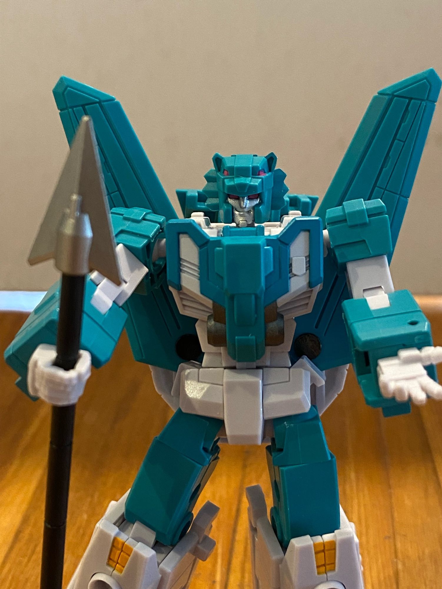 Image of the 3rd party action figure of the Transformers Breastforce character Leozack by Iron Factory. Leozack is holding his arms in front of him, one clasping an upright spear weapon and the other palm up towards the camera. Leozack is smirking at the camera.