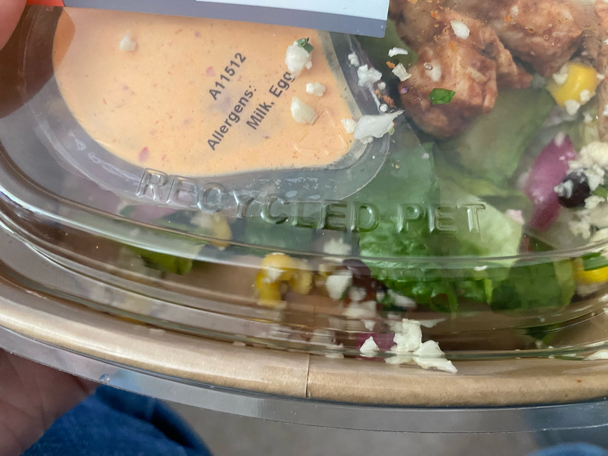 Close-up of the plastic lid on a shop-bought salad. The lid says "RECYCLED PET"