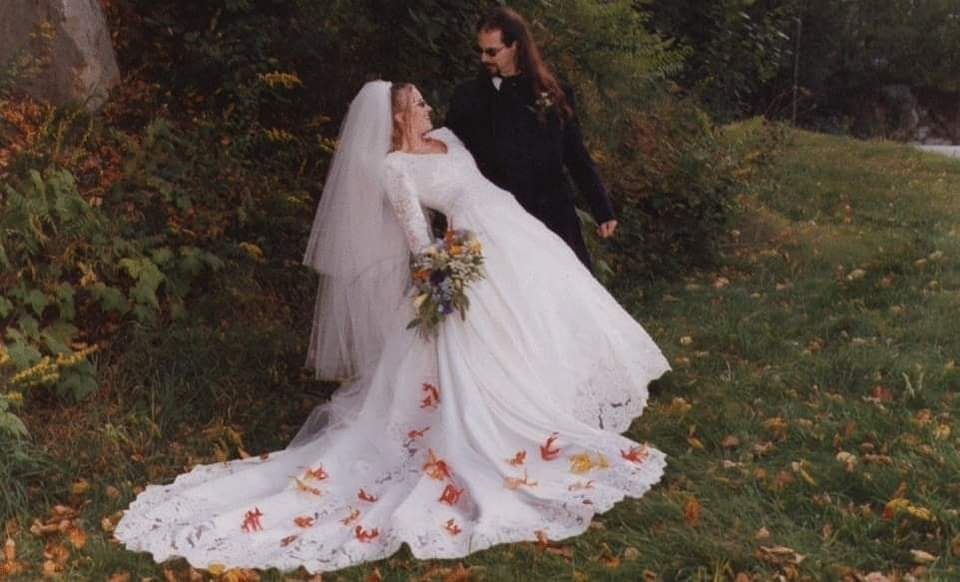 A wedding photo of myself and my spouse in traditional gown and tuxedo, but scattered with autumn leaves and we are wearing sunglasses