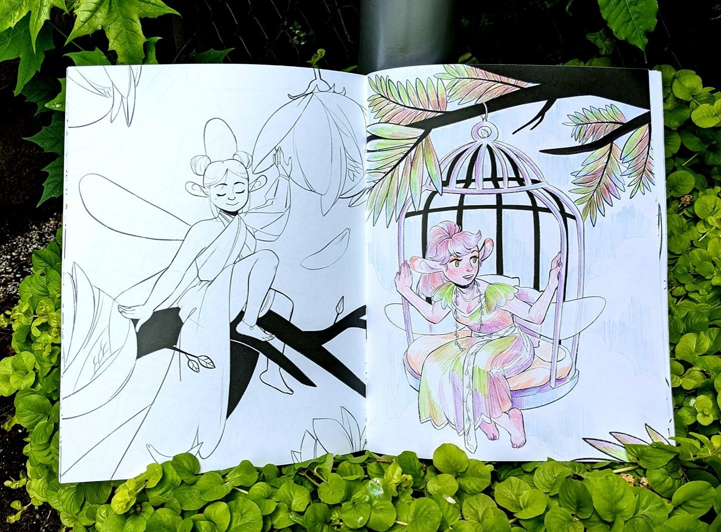 photo of a spread from the coloring book, surrounded by greenery. the left page is left uncolored, while the right is colored with colored pencils to demonstrate paper quality.