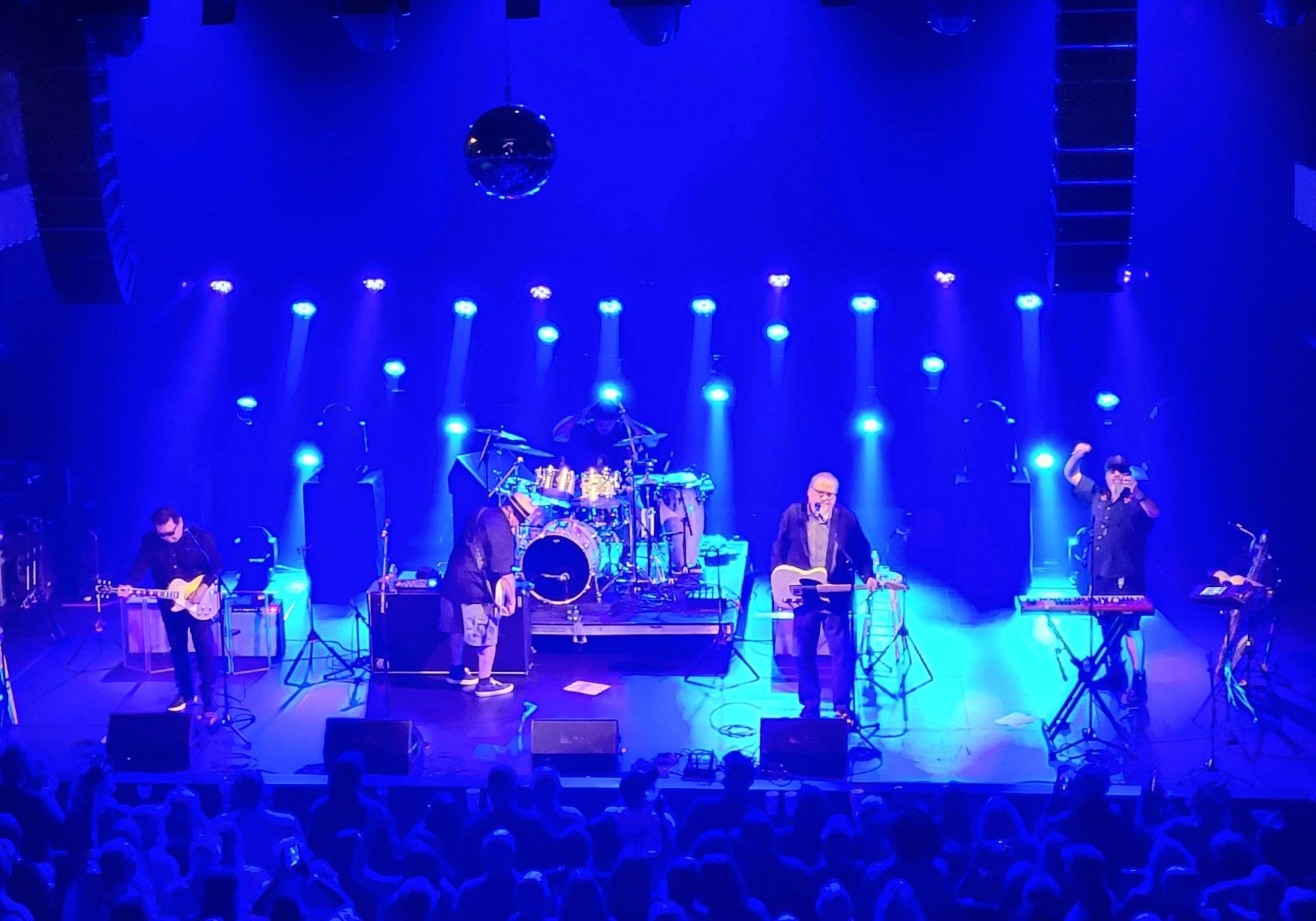 Blue stage lights illuminate 5 men on stage