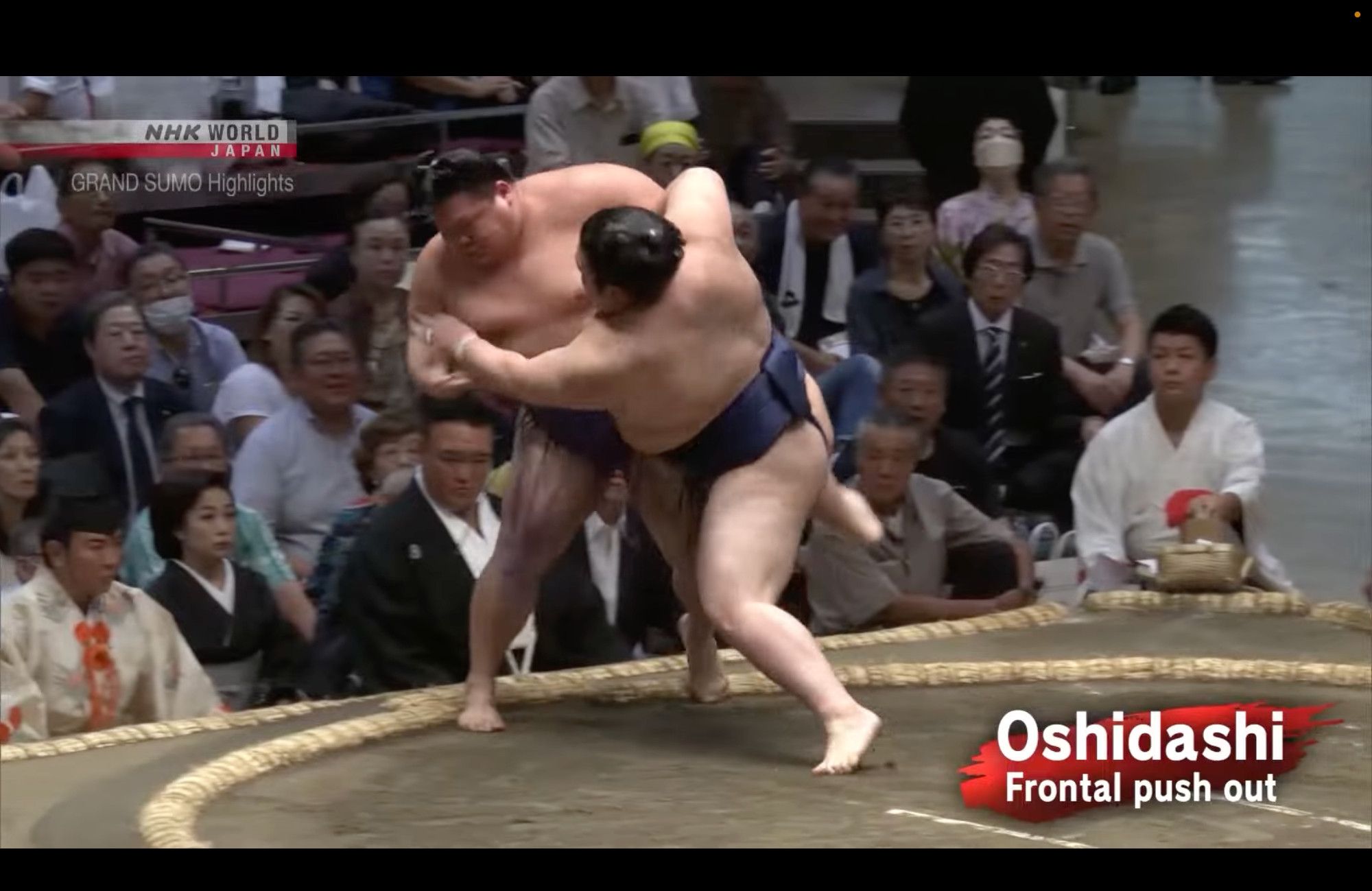 A sumo wrestler makes a final violent shove while balancing on one athletically balanced foot to drive his opponent suddenly out