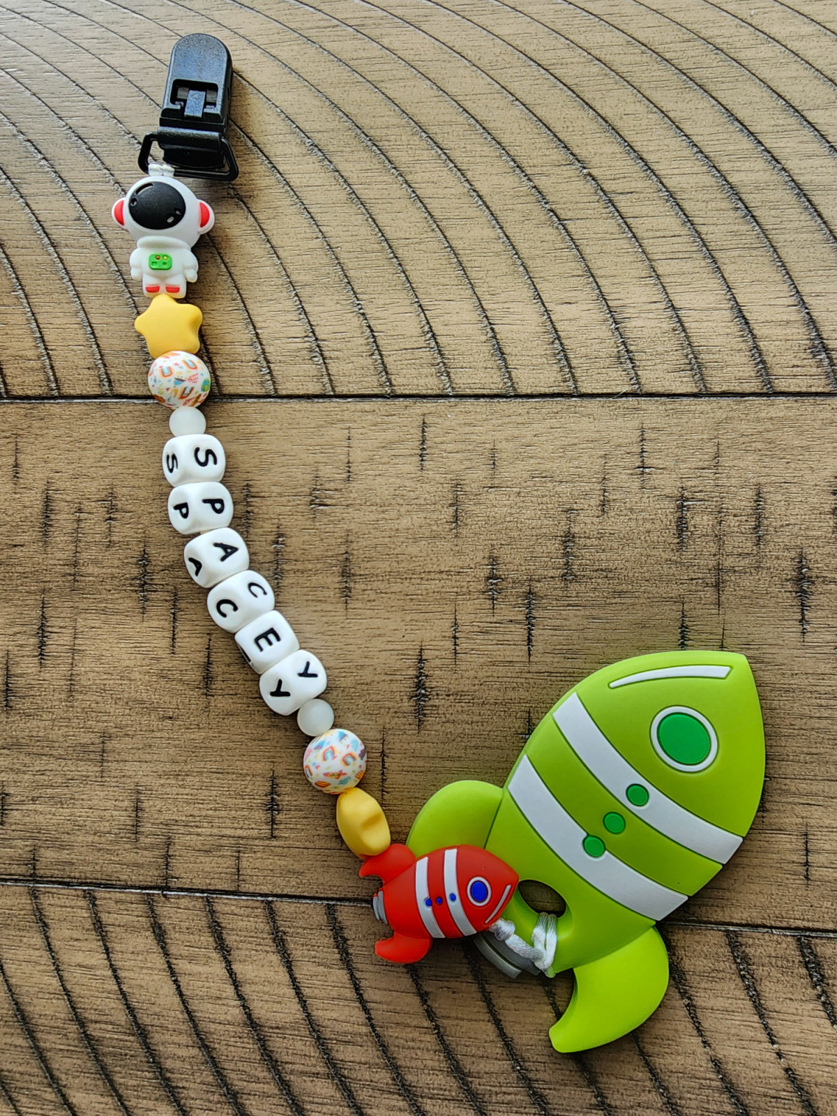 Feeling Spacey, Teether with the beaded words "spacey", A 3D astronaut, a red rocket ship, and a green rocketship teether