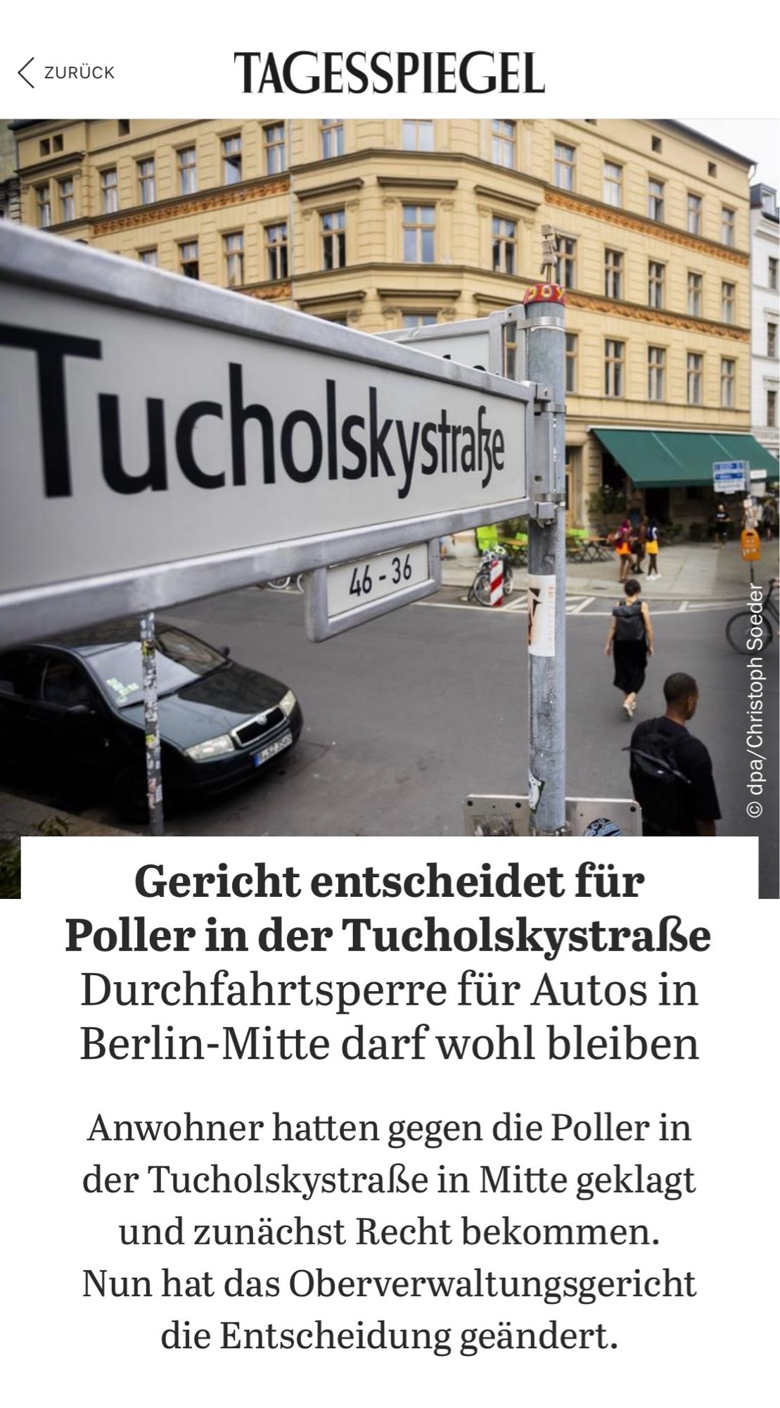 Screenshot Tagesspiegel-Artikel:
Titelbild zeigt die Kreuzung Auguststr./Tucholskystr. Im Vordergrund das Straßenschild der T-Straße. Das Foto ist verzerrt wie durch ein Fischauge. 
Darunter der Titel und Untertitel:
„Gericht entscheidet für Poller in der Tucholskystraße Durchfahrtsperre für Autos in Berlin-Mitte darf wohl bleiben
Anwohner hatten gegen die Poller in der Tucholskystraße in Mitte geklagt und zunächst Recht bekommen.
Nun hat das Oberverwaltungsgericht die Entscheidung geändert.“