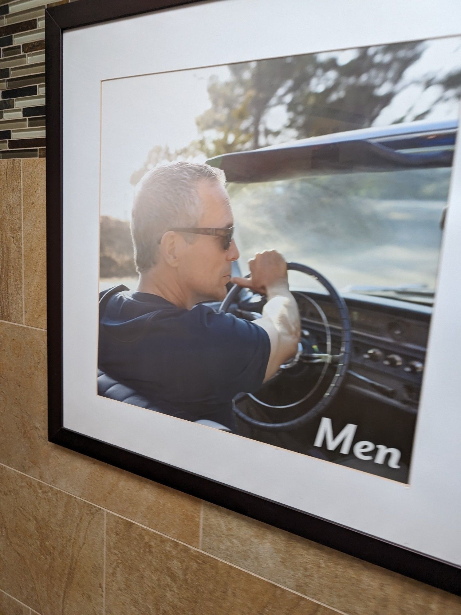 Hung photo of a man driving a car. The caption reads "Men"