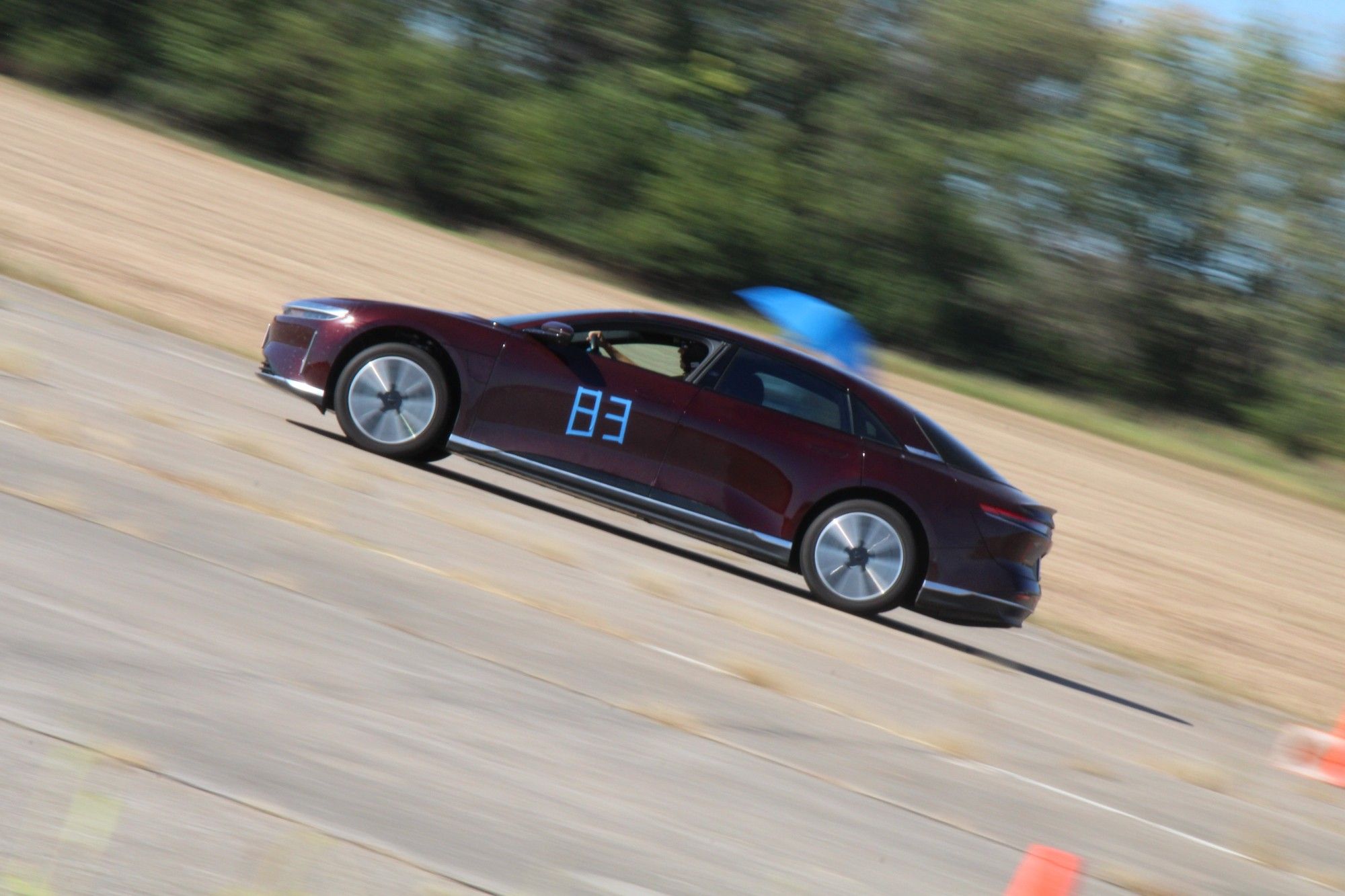 A side profile of a purple Lucid Air going thru an autocross course.