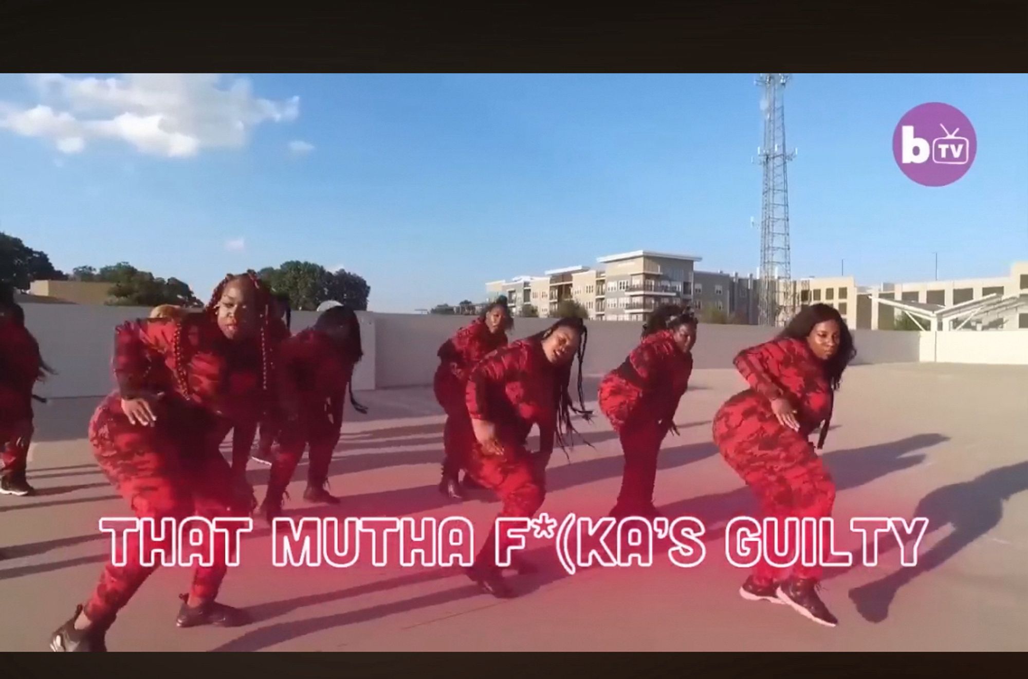 video snap from Madison McFerrin's extended version of "Guilty"  featuring six? seven? dancers in red camo jumpsuits dancing on a roof with the caption THAT MUTHA  F*(KA'S GUILTY superimposed across the bottom third.