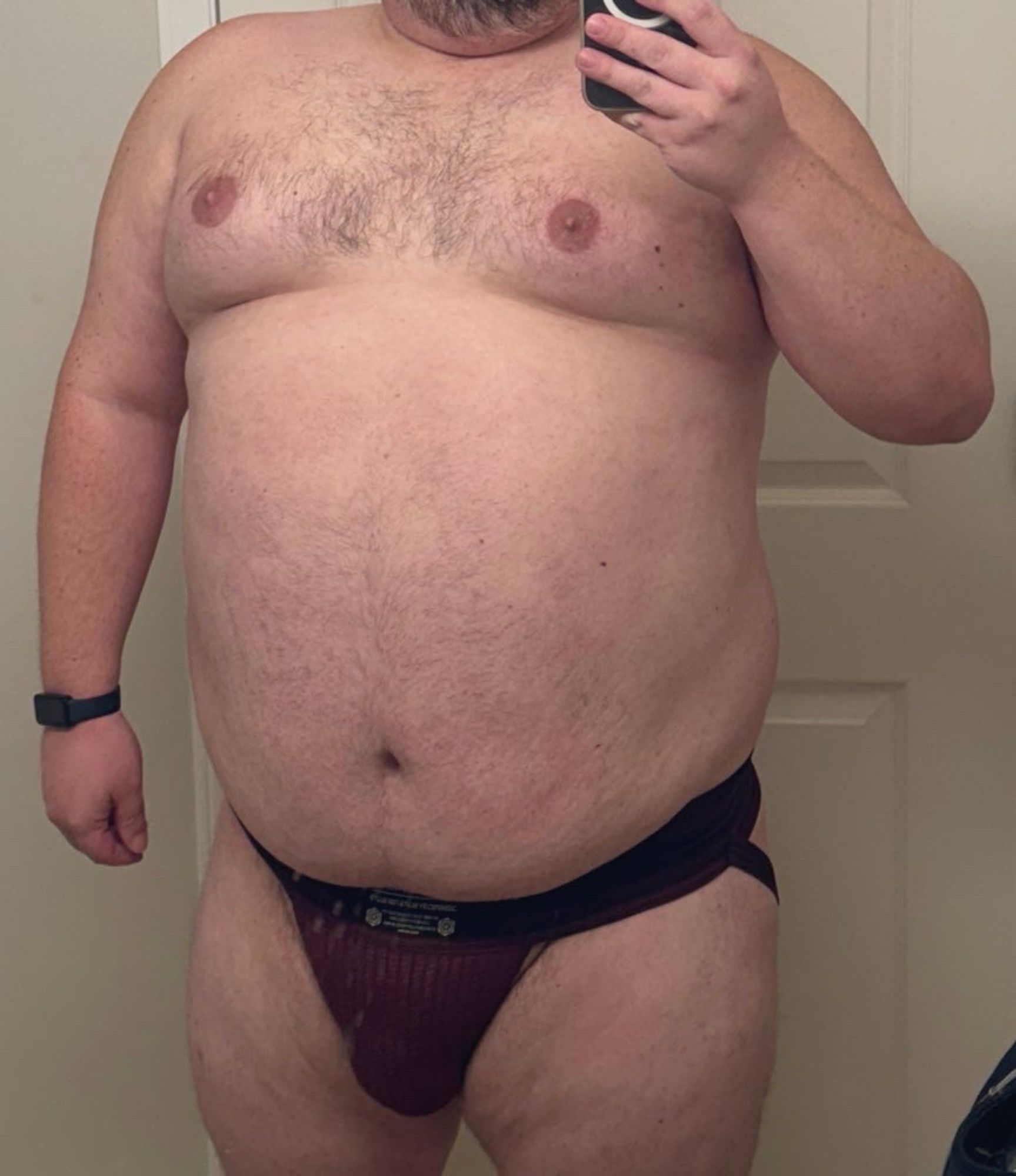 Bear wearing a crimson red jockstrap takes a mirror selfie