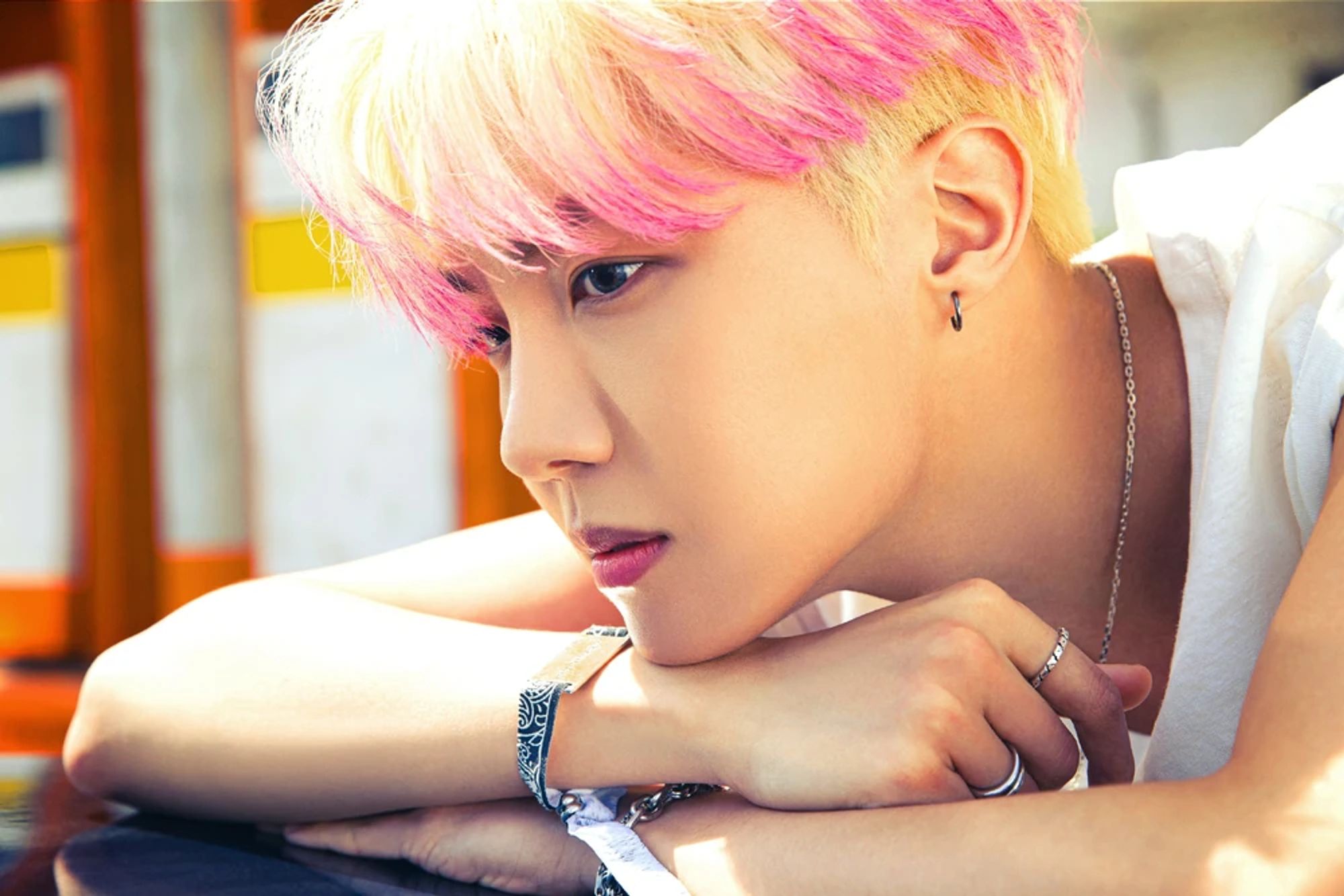 J-Hope Butter concept from 2021. He has blond hair with pink highlights. It's a close-up shot of him resting his head on his bare arms. The sun is shining down on him