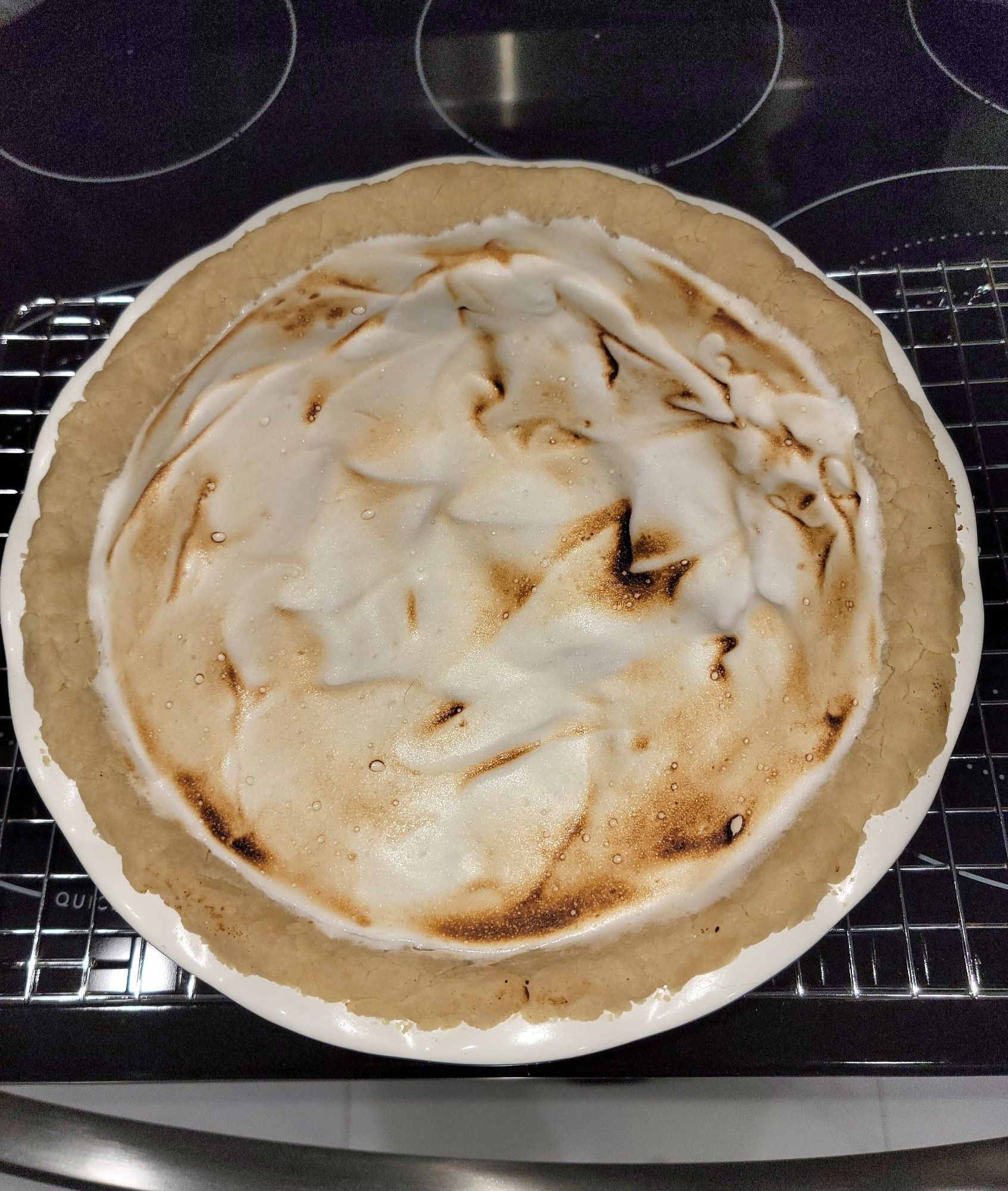 View of top of lemon meringue pie on cooling rack on stove top