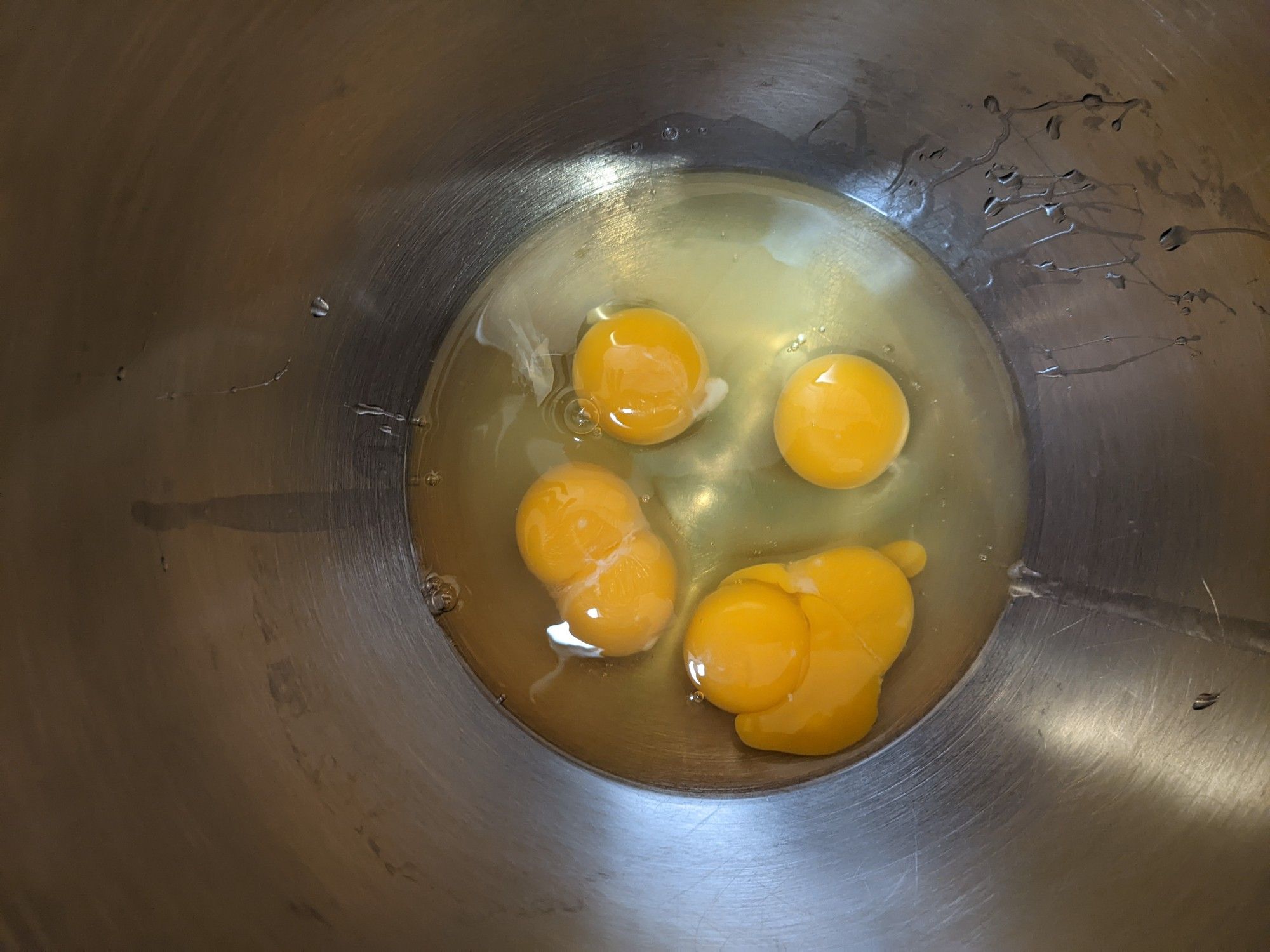 KitchenAid mixer bowl containing four eggs, two of which have double yolks