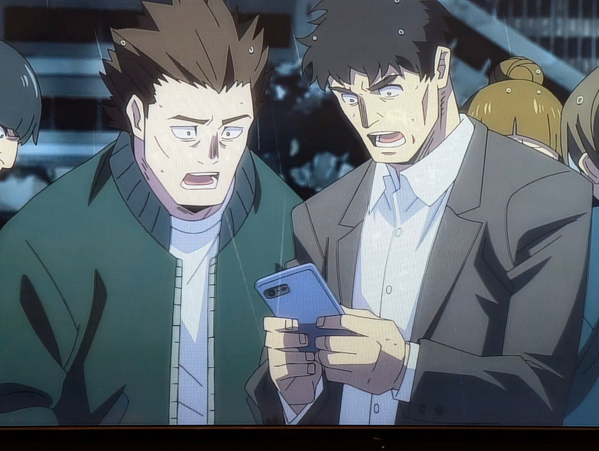 A photo of my TV showing two men looking at a smartphone looking SHOCKED