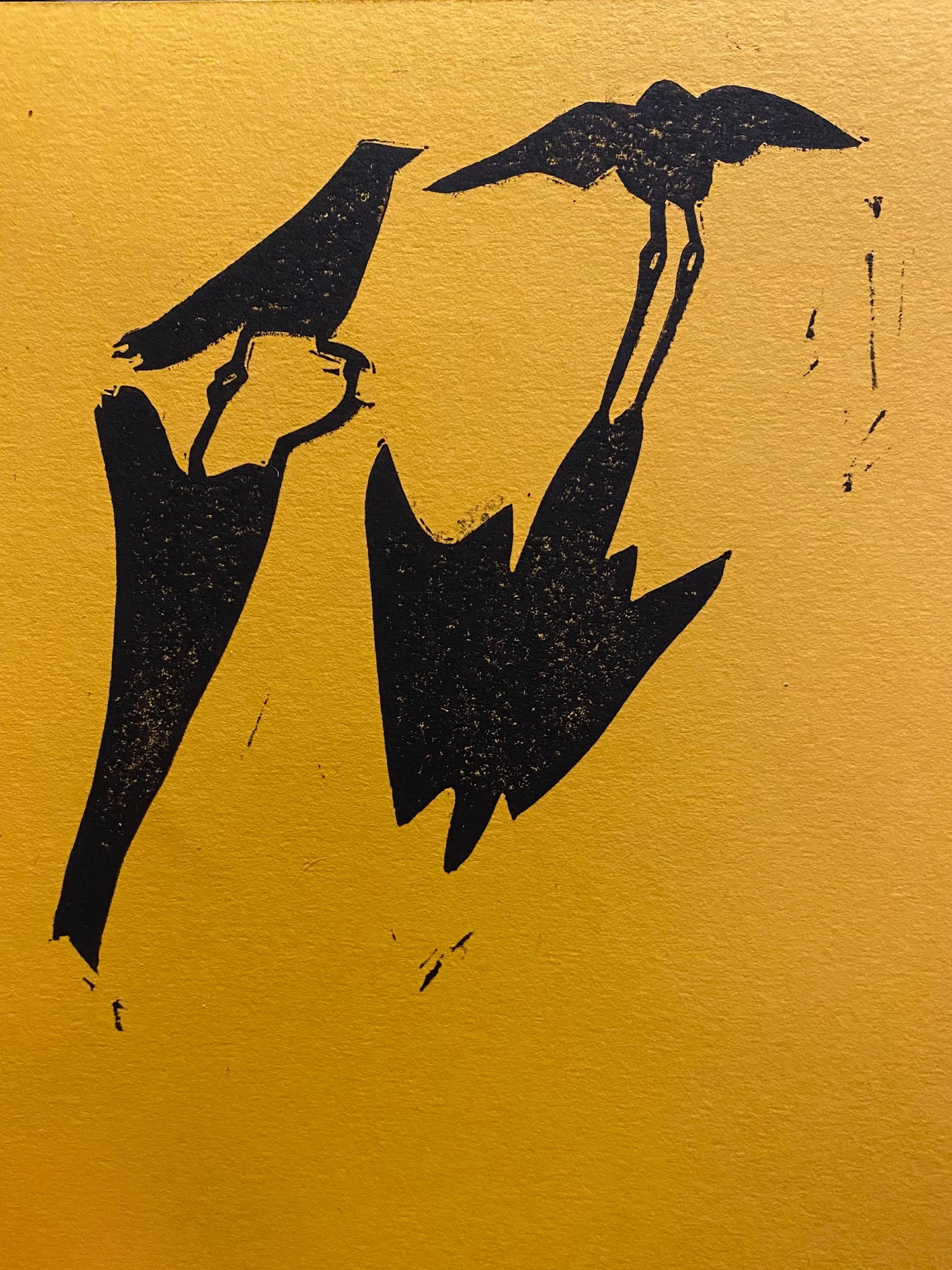 lino print on gold paper of two crows and their long shadows