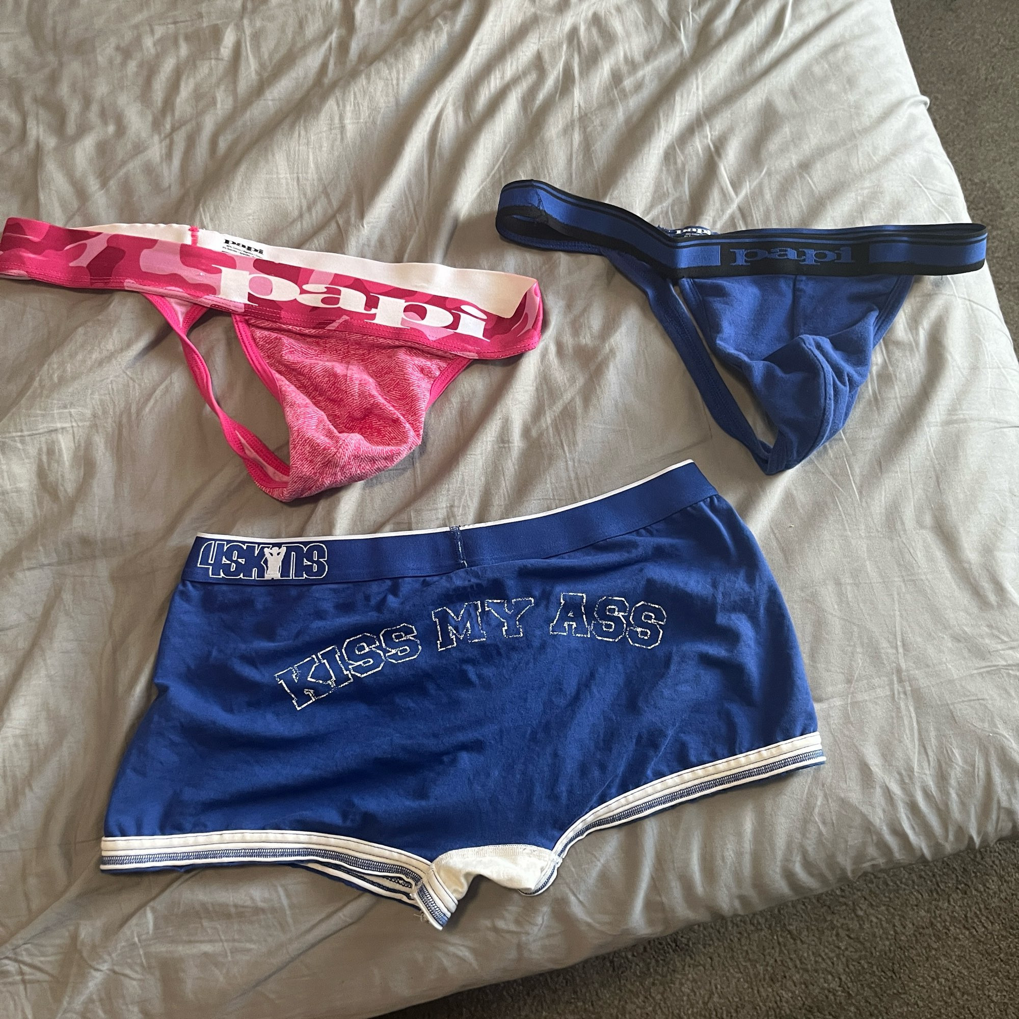 The three aforementioned pairs of underwear, a pink thong, a dark blue thong, and a white and blue pair of trunks