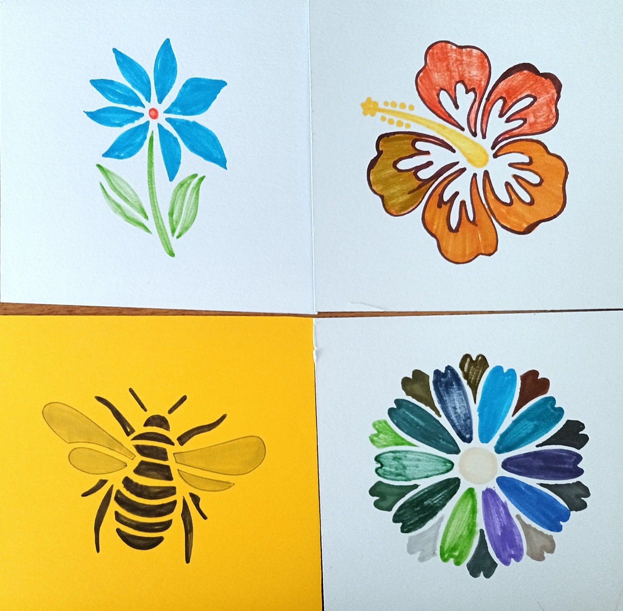 4 square cards
Top left blue flower with stem & leaves onlight blue background
Top right
Orange flowerhead on light blue background
Bottom left bee on yellow background
Bottom right flowerhead in mix of blue, green, purple and grey on light blue background