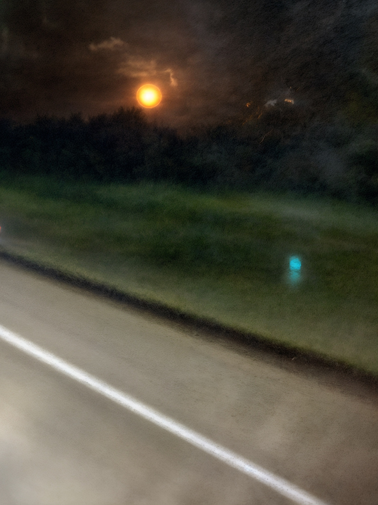 A photograph of the moon taken from within a moving vehicle.