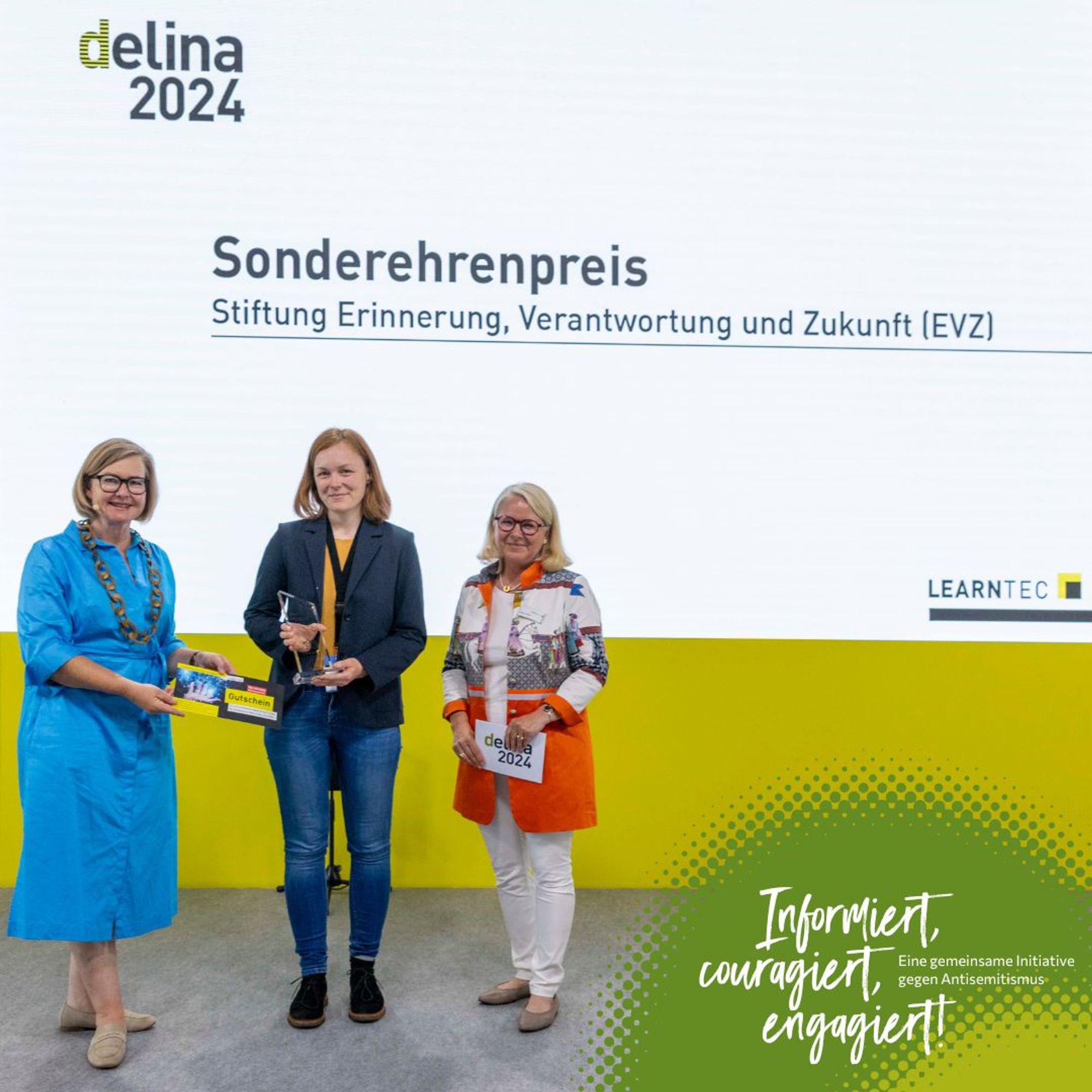 eine Gruppe von Frauen steht vor einer weißen und grünen Wand. Auf dieser steht "delina 2024, Sonderehrenpreis, Stiftung Erinnerung, Verantwortung und Zukunft (EVZ)"