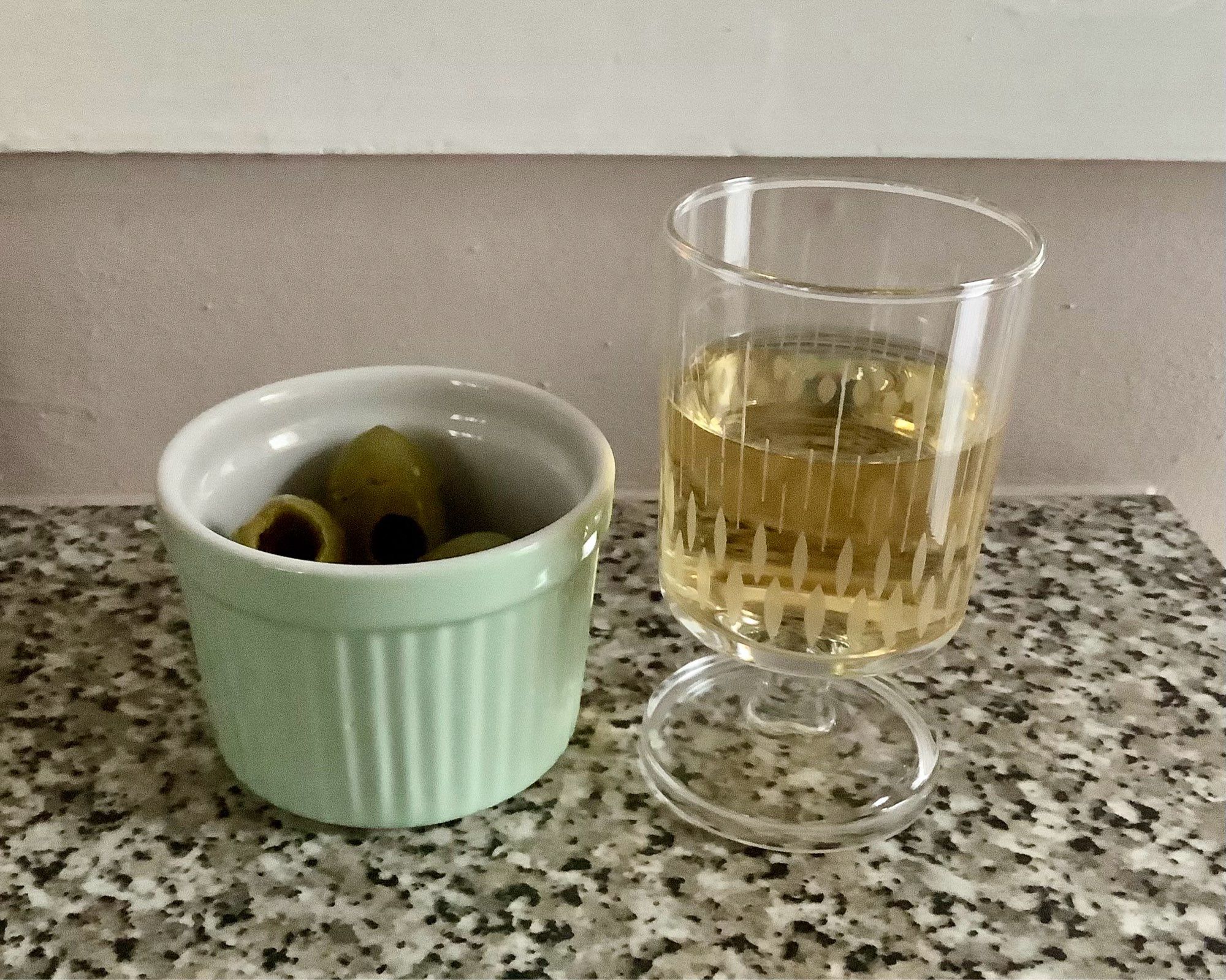 Green pot of green olives and a glass of dry sherry