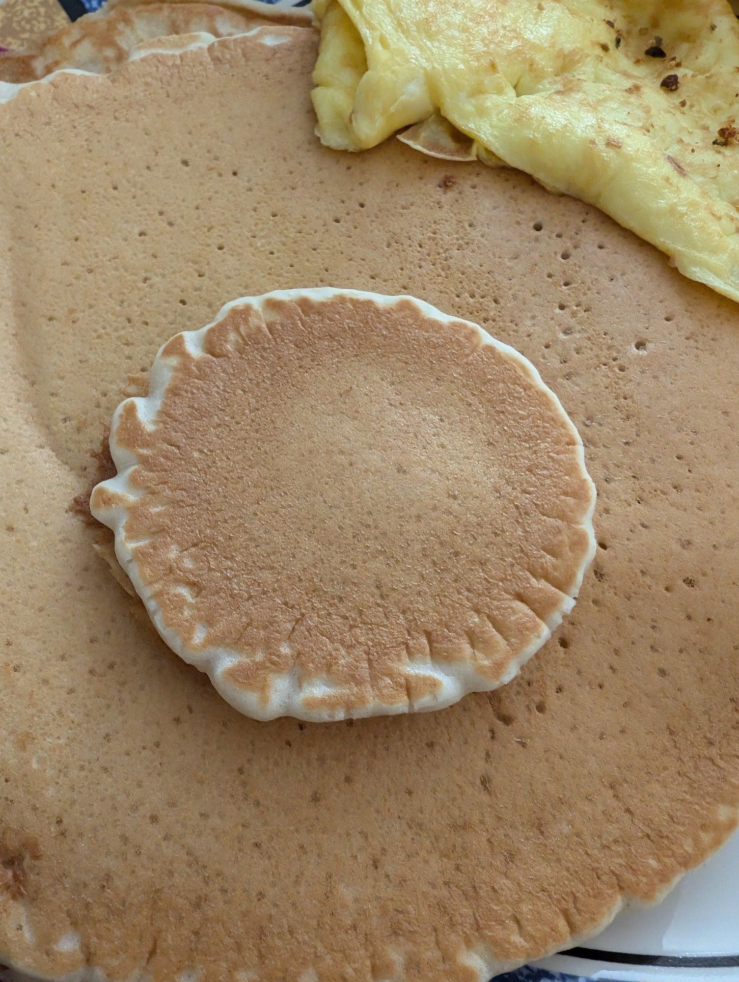 A tiny pancake on top of a much larger pancake