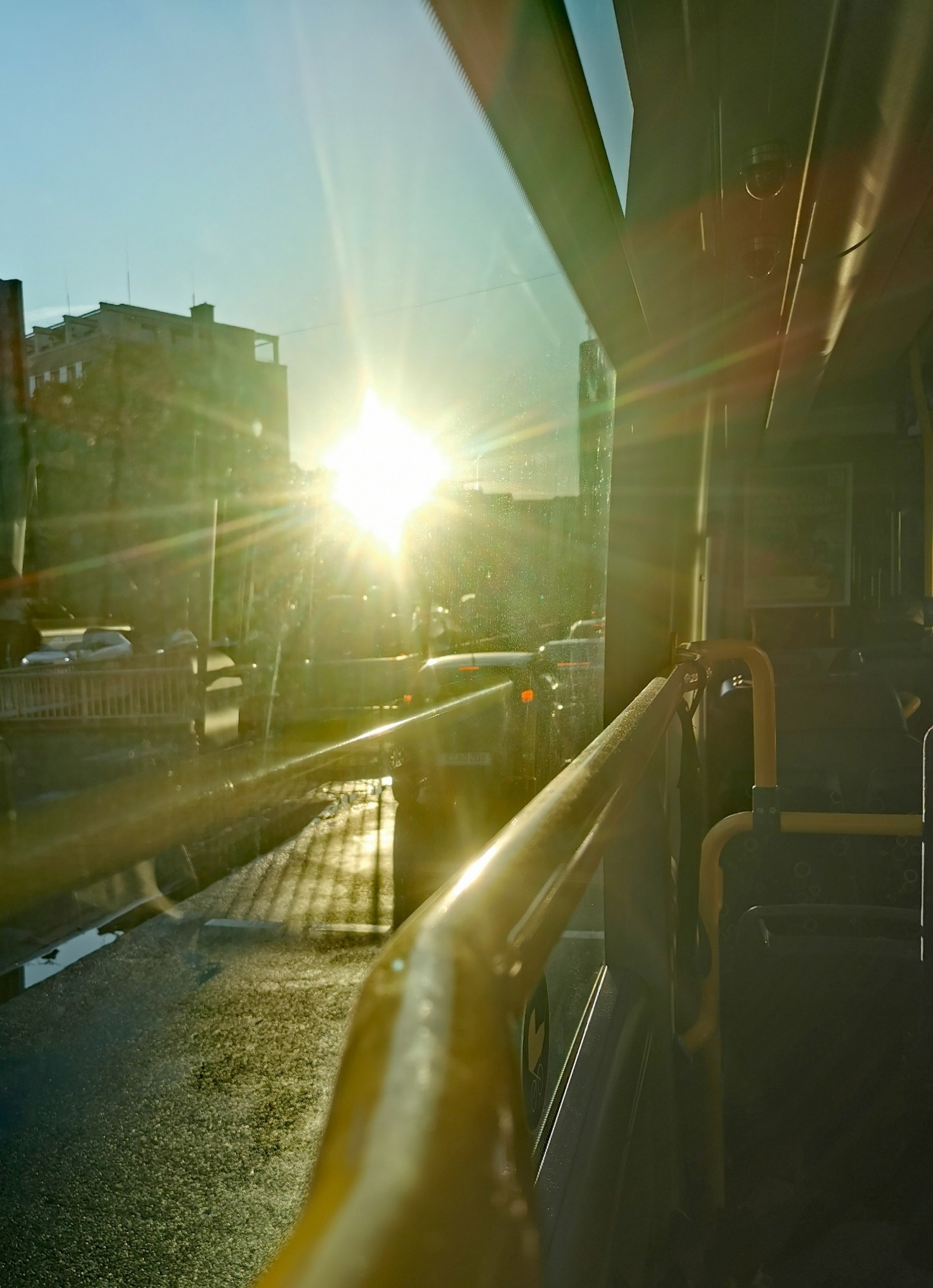 Foto aus einem Bus heraus auf eine Straße im Feierabendverkehr im Zwielicht der untergehenden Abendsonne.