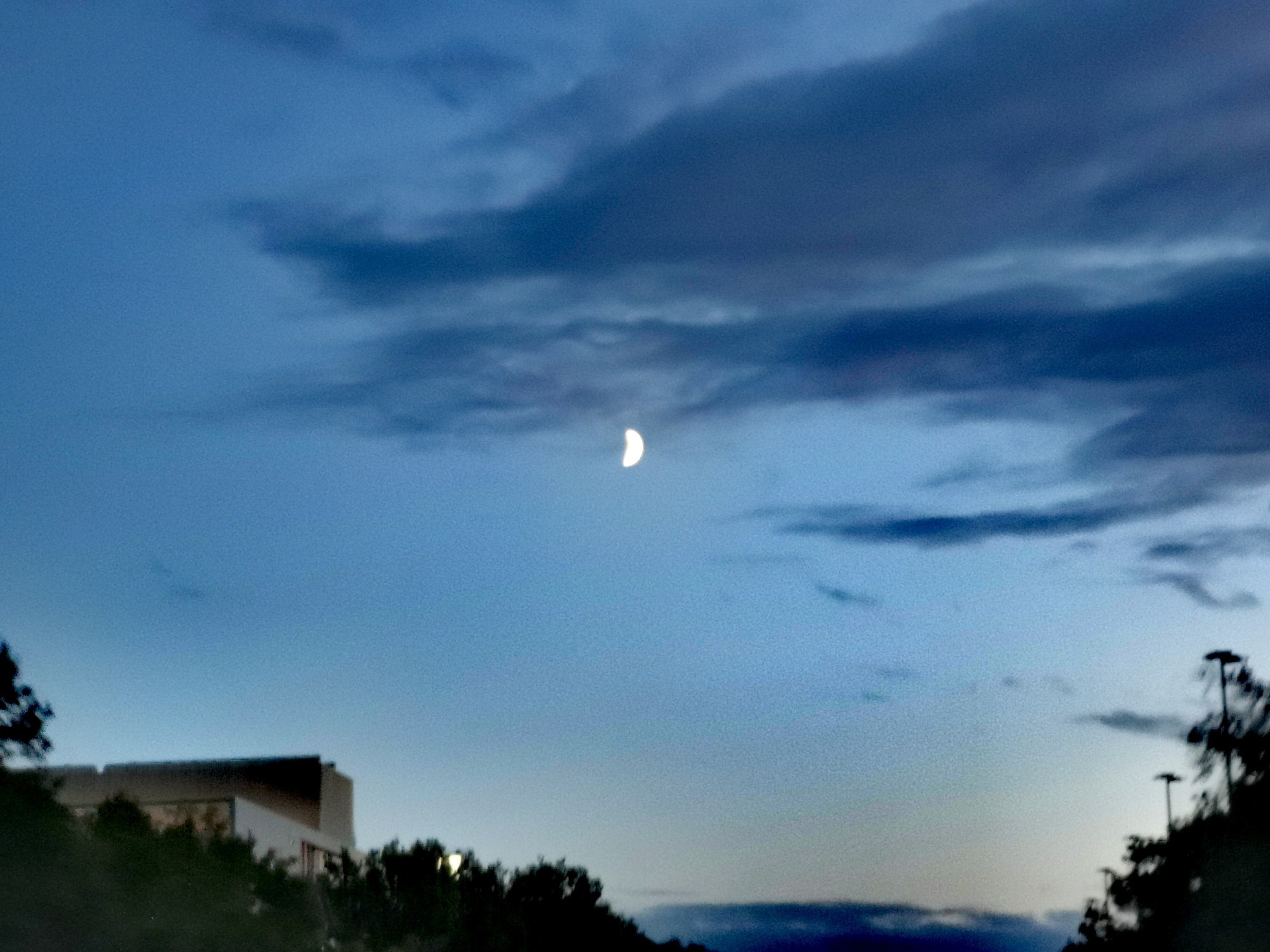 Ein Foto des Abendhimmels, mit einem Halbmond im Zentrum.