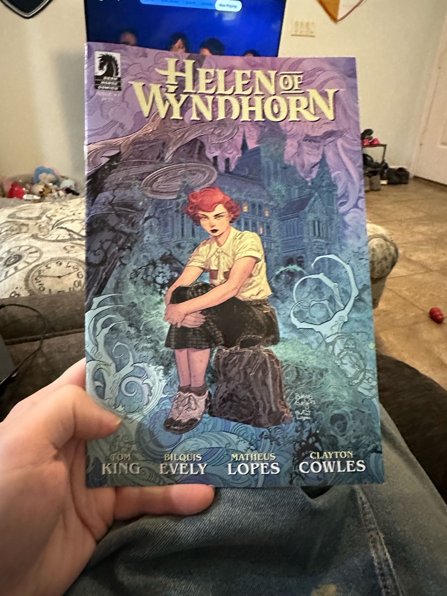 The cover of Helen of Wyndhorn #1, featuring the red headed teen heroine sitting on a rock in front of a gothic mansion while spooky stuff happens around her.