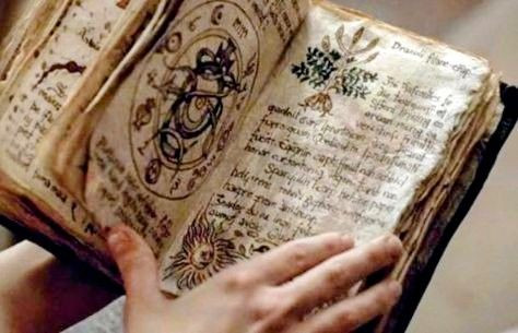 Someone reading an old, weathered book that appears to be a magical grimoire. 