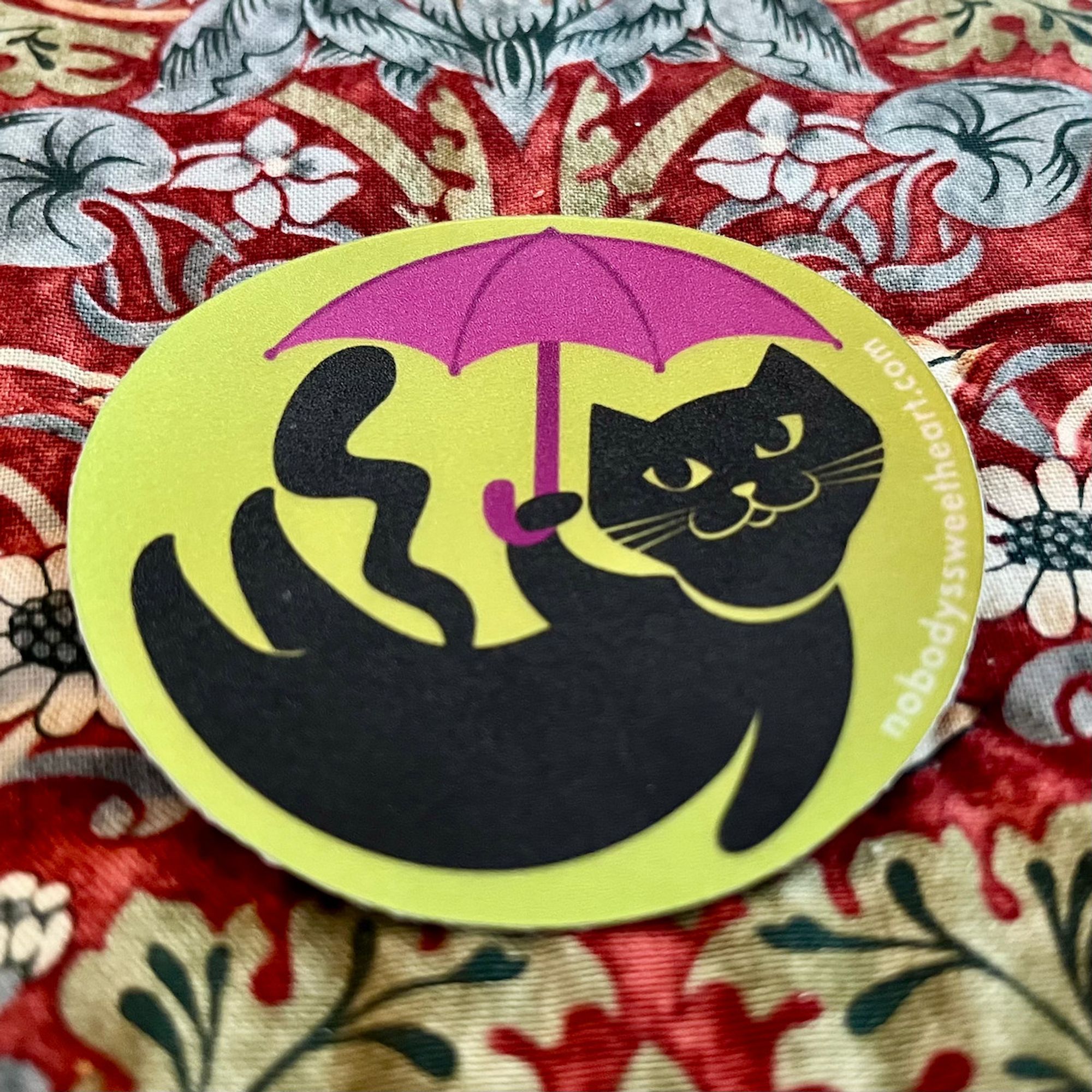 shiny sticker of a black cat holding a pink umbrella