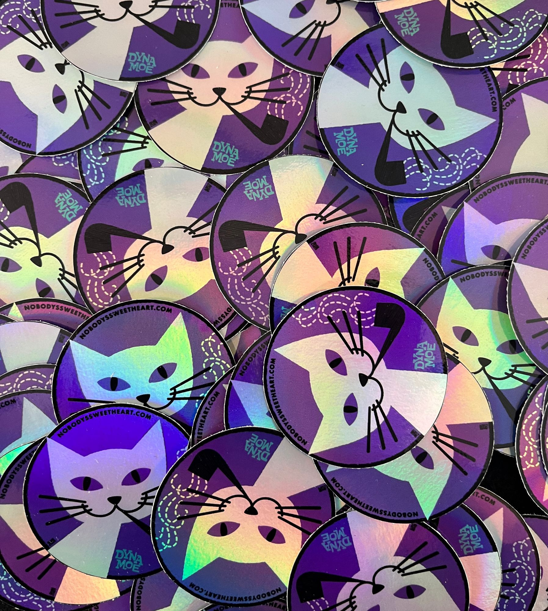 Lots of cat-smoking-a-pipe stickers in a big pile. Shiny and purr-ple.