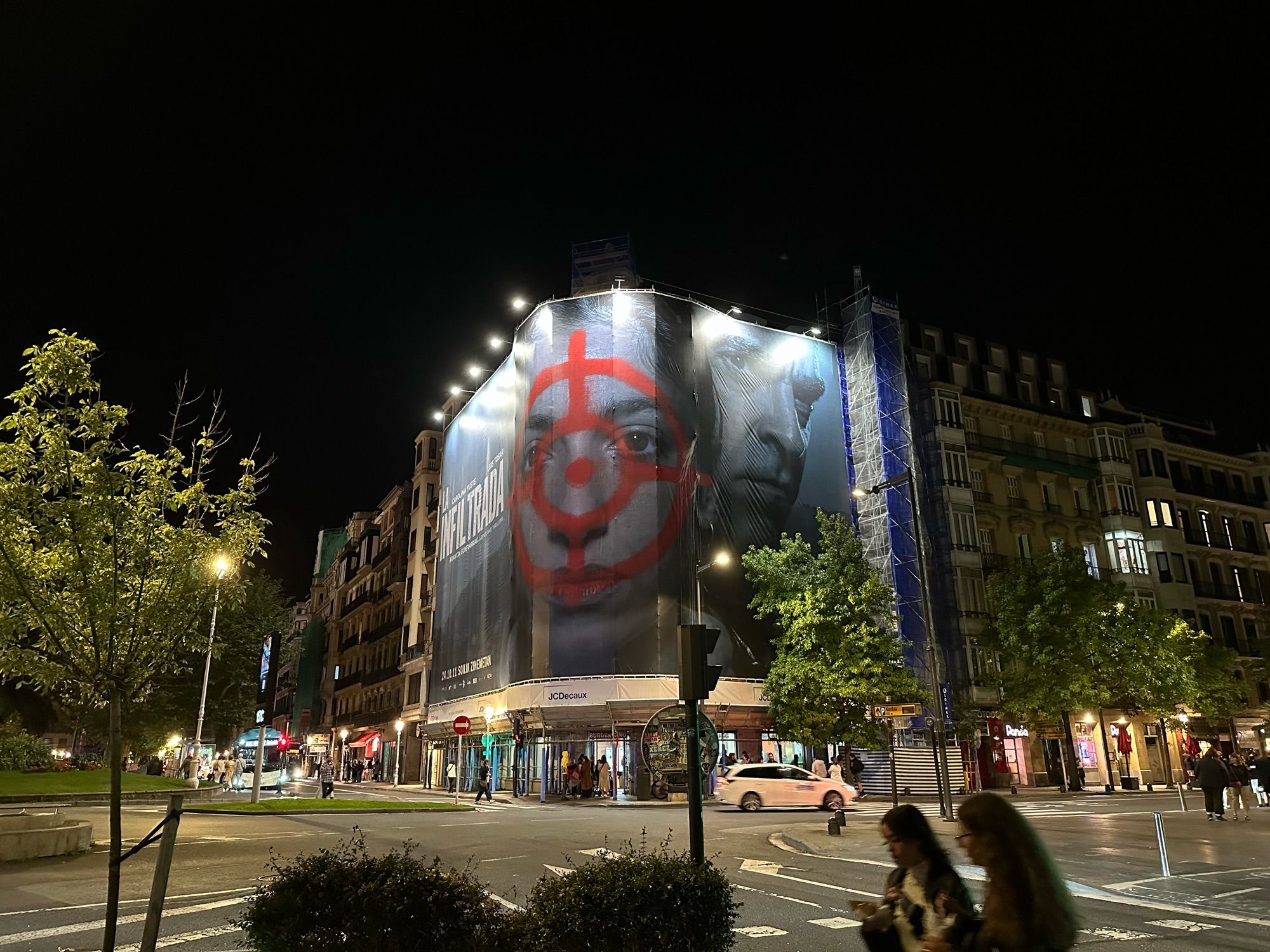 Kreuzung in San Sebastián nachts mit Kinowerbung an Hausfassade