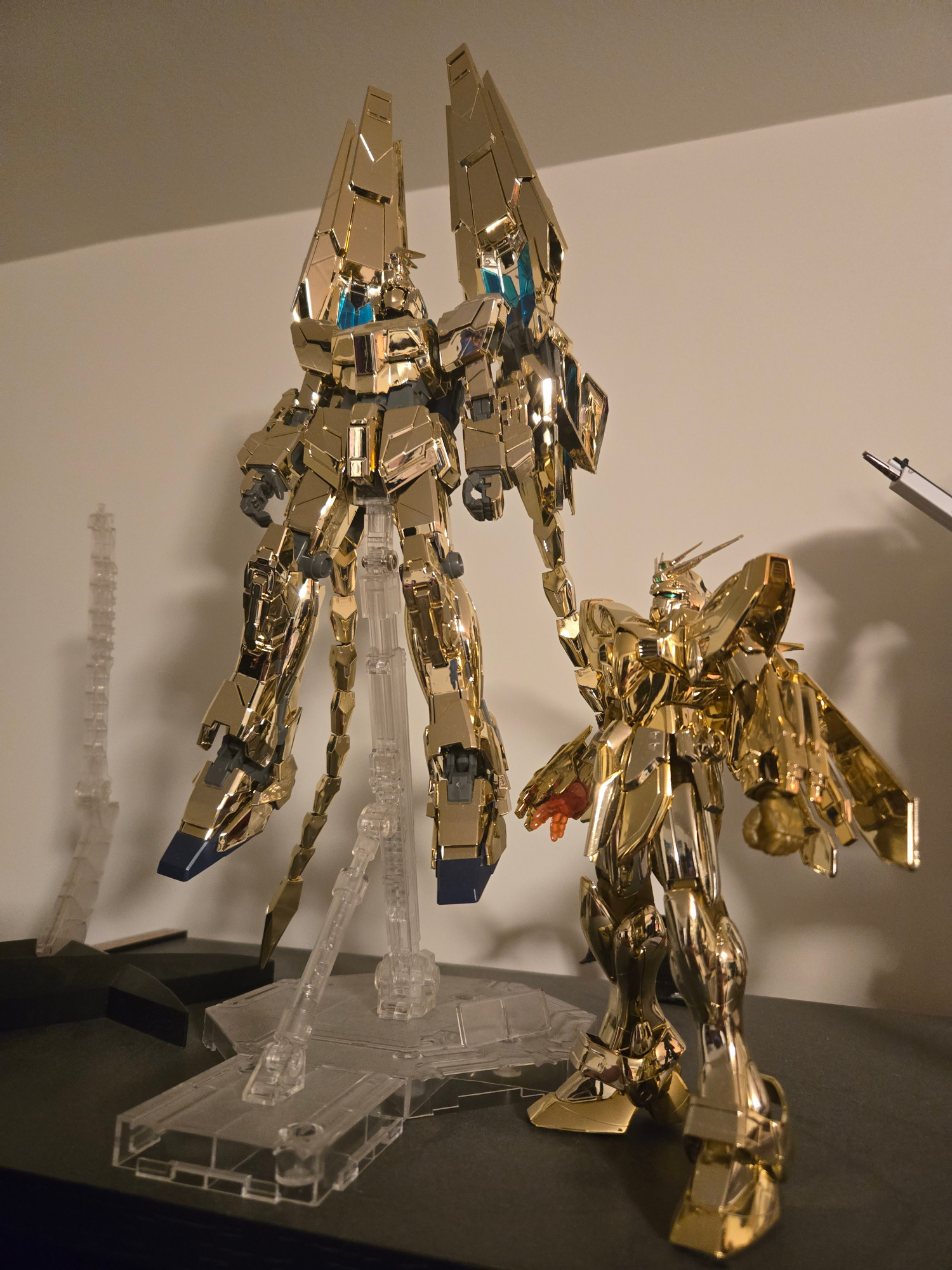 A photo of the MG Phenex with aftermarket tails and the MG God Gundam, both of which are plated gold model kits