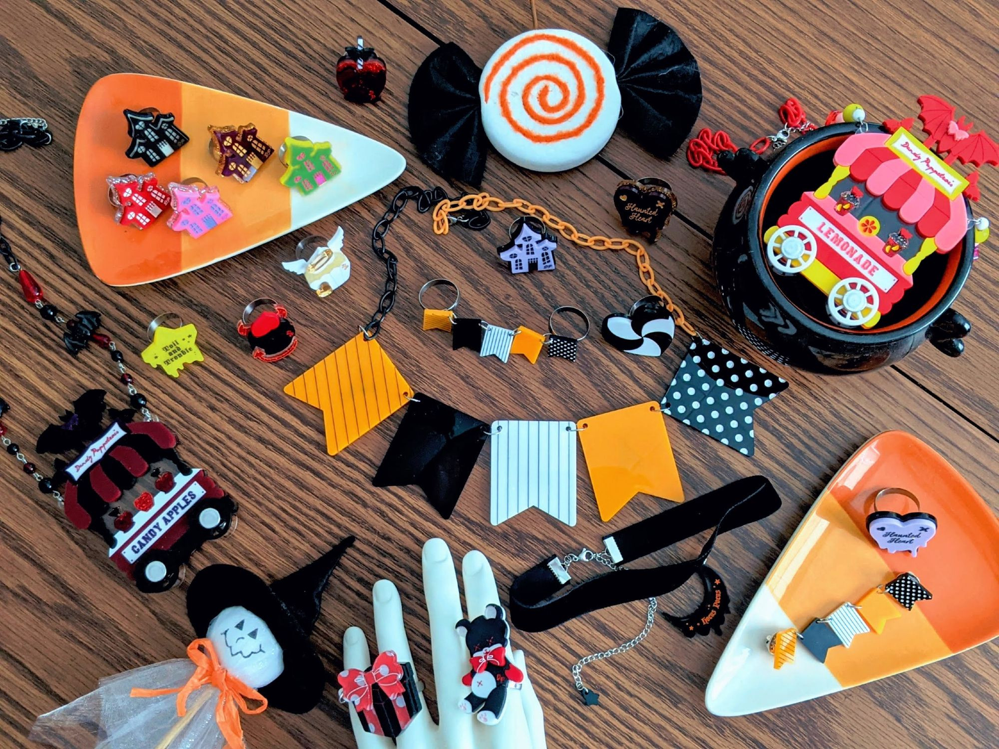 Various jewelry designs across a table with Halloween themed pottery.