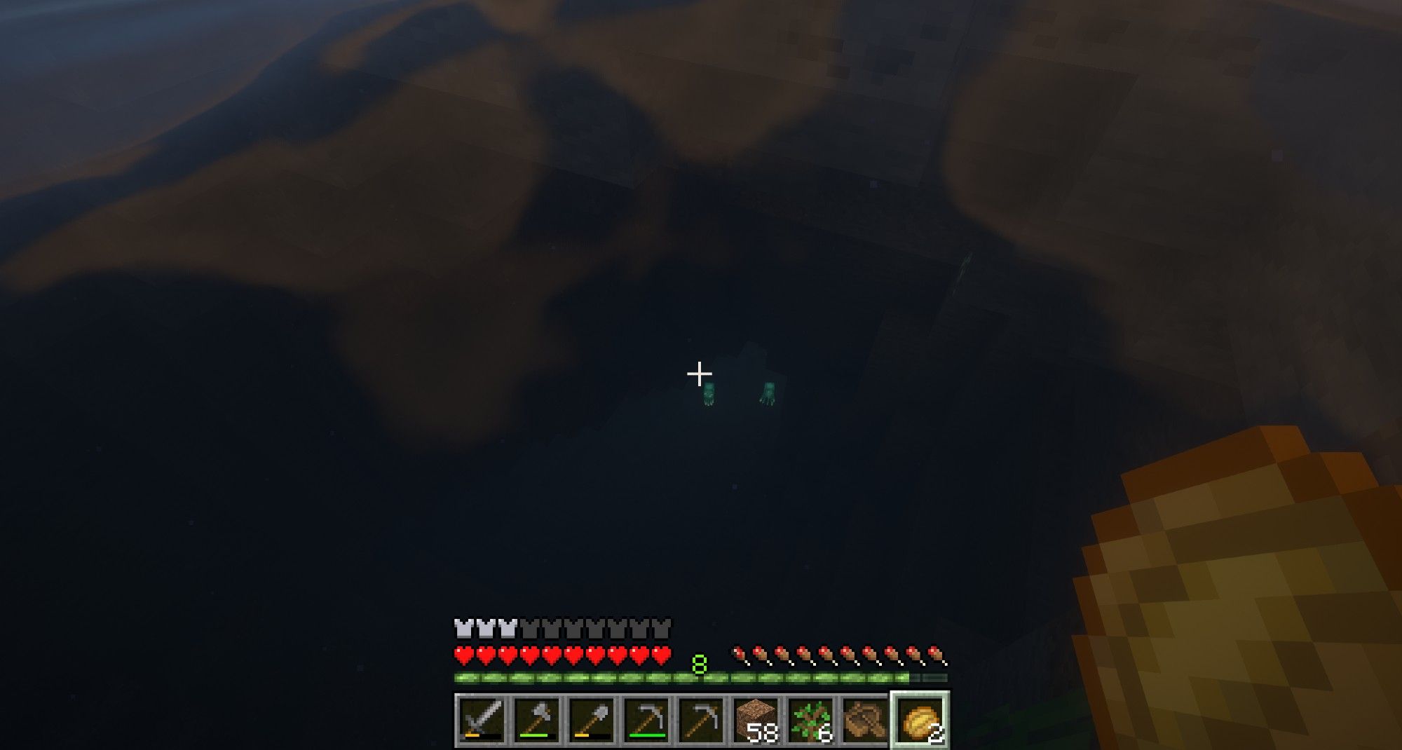 Screenshot aus dem Spiel Minecraft:
Blick auf zwei Glow Squids tief unten im dunklen Gewässer und der Minecraft-UI im Vordergrund (und Baked Potato in der Hand)