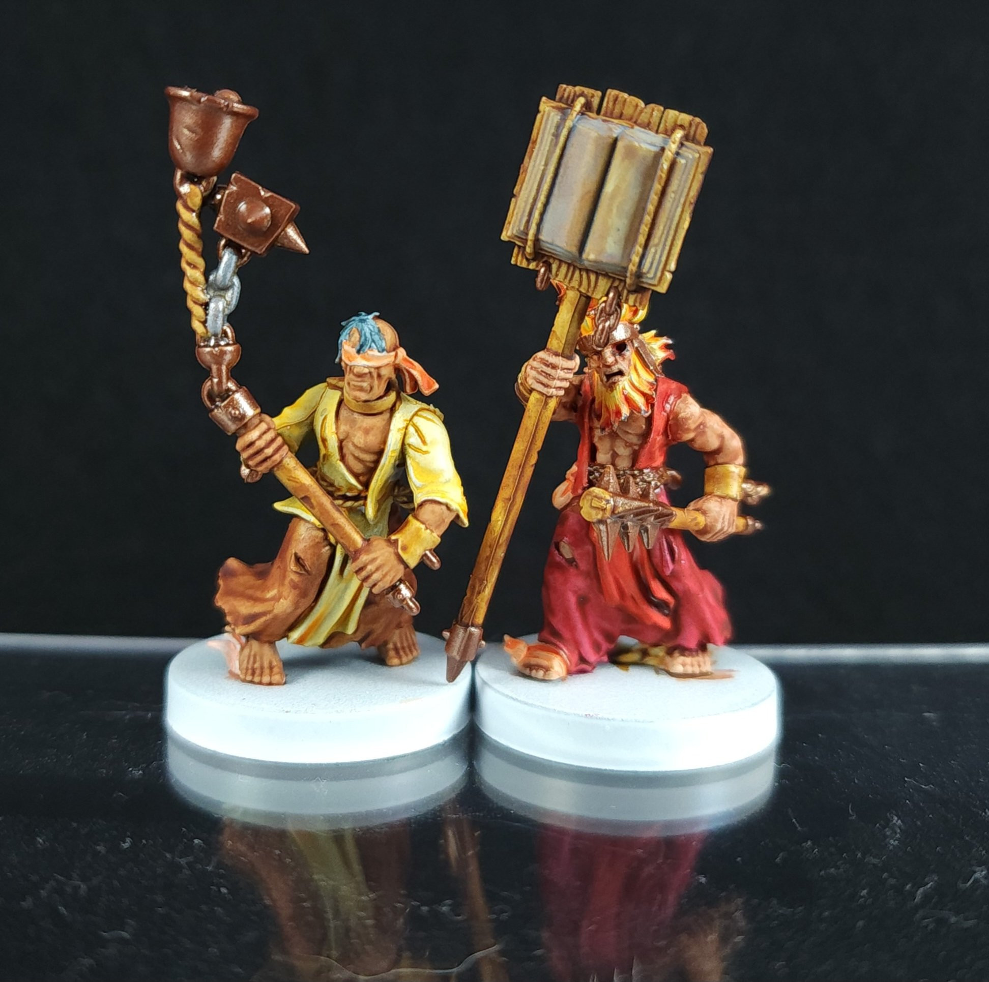 Two painted Games Workshop miniatures. Flagellants, in yellows, oranges and reds.