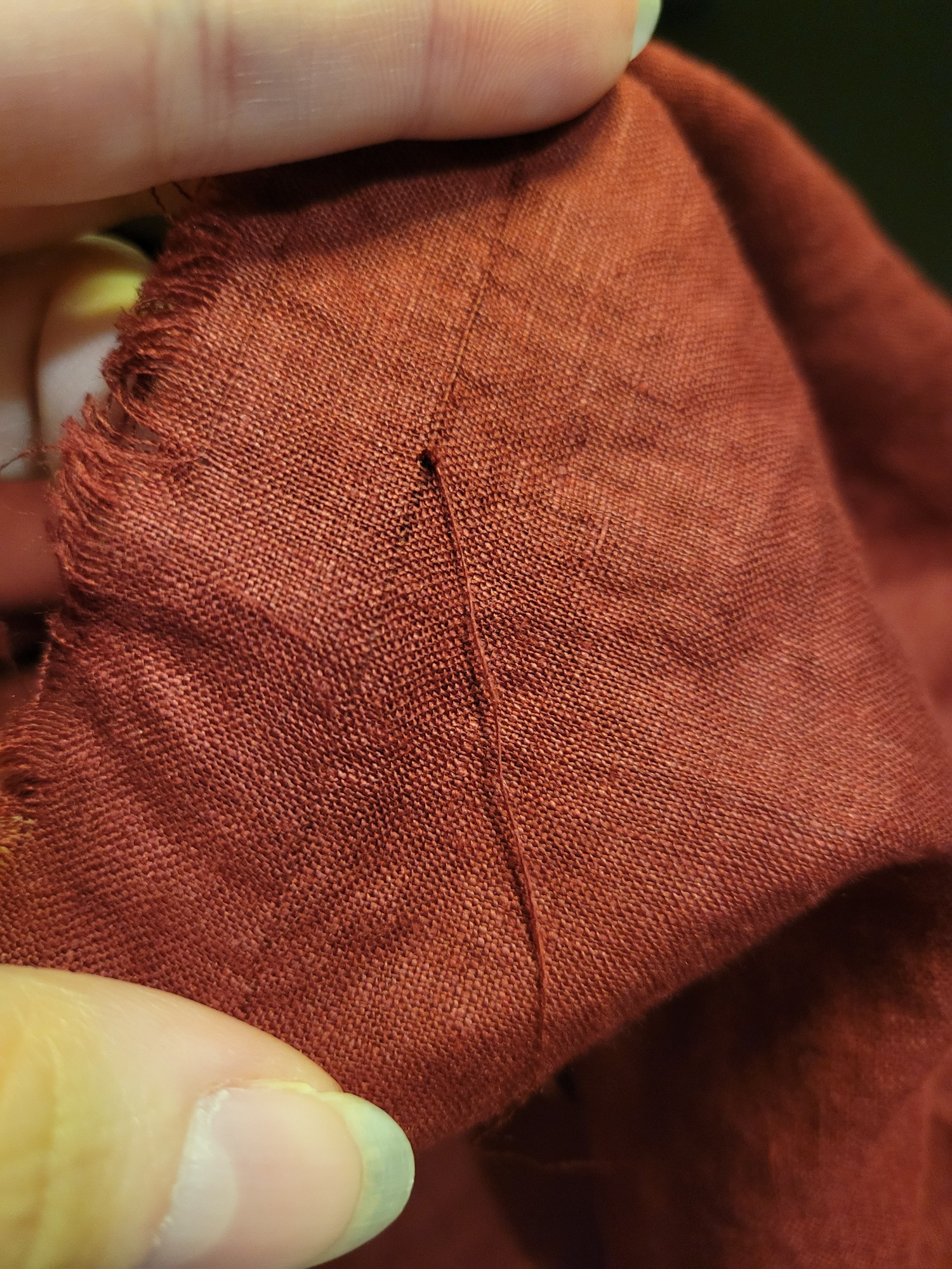 Red linen with a thread pulled to find the grainline.