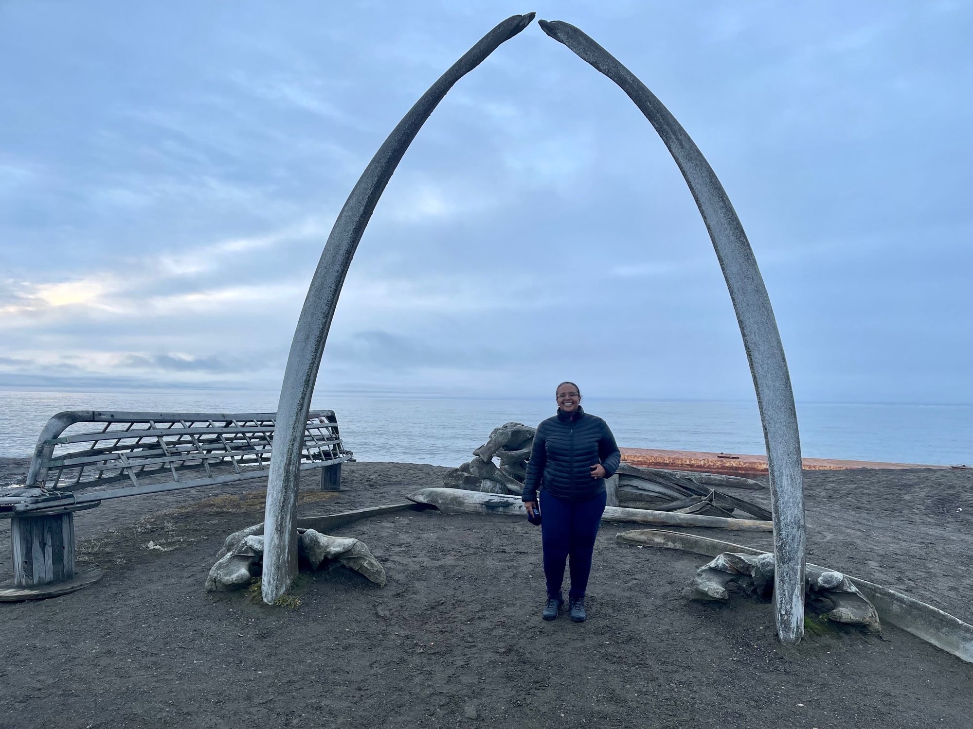 AAB standing in front of a whale-bone arch on the cost of the Arctic Ocean in Utqiagvik, AK. The “Gateway to the Arctic”.