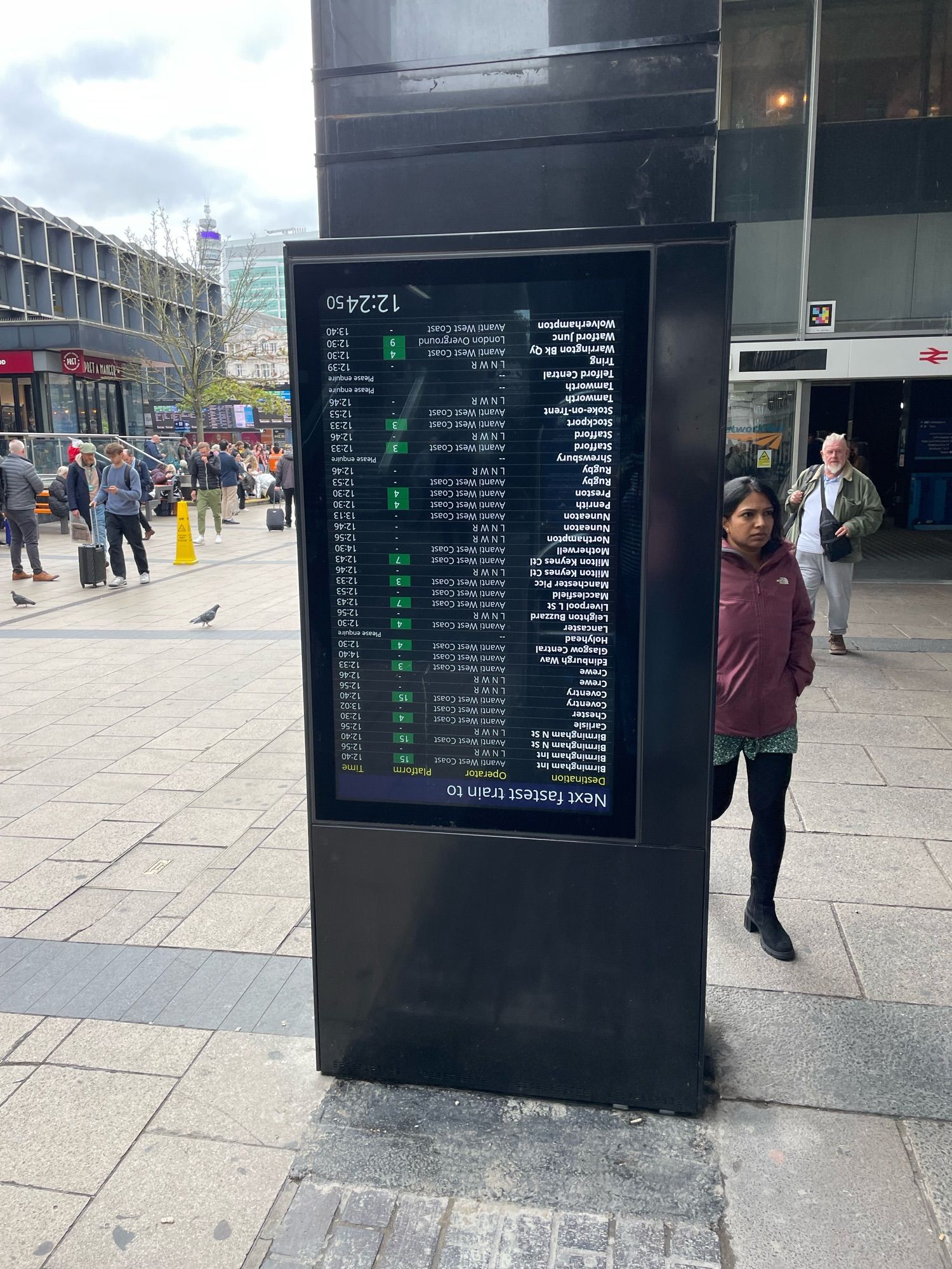 A “next fastest train to” electronic display. The whole of the display has been rotated through 180° so it is upside down.