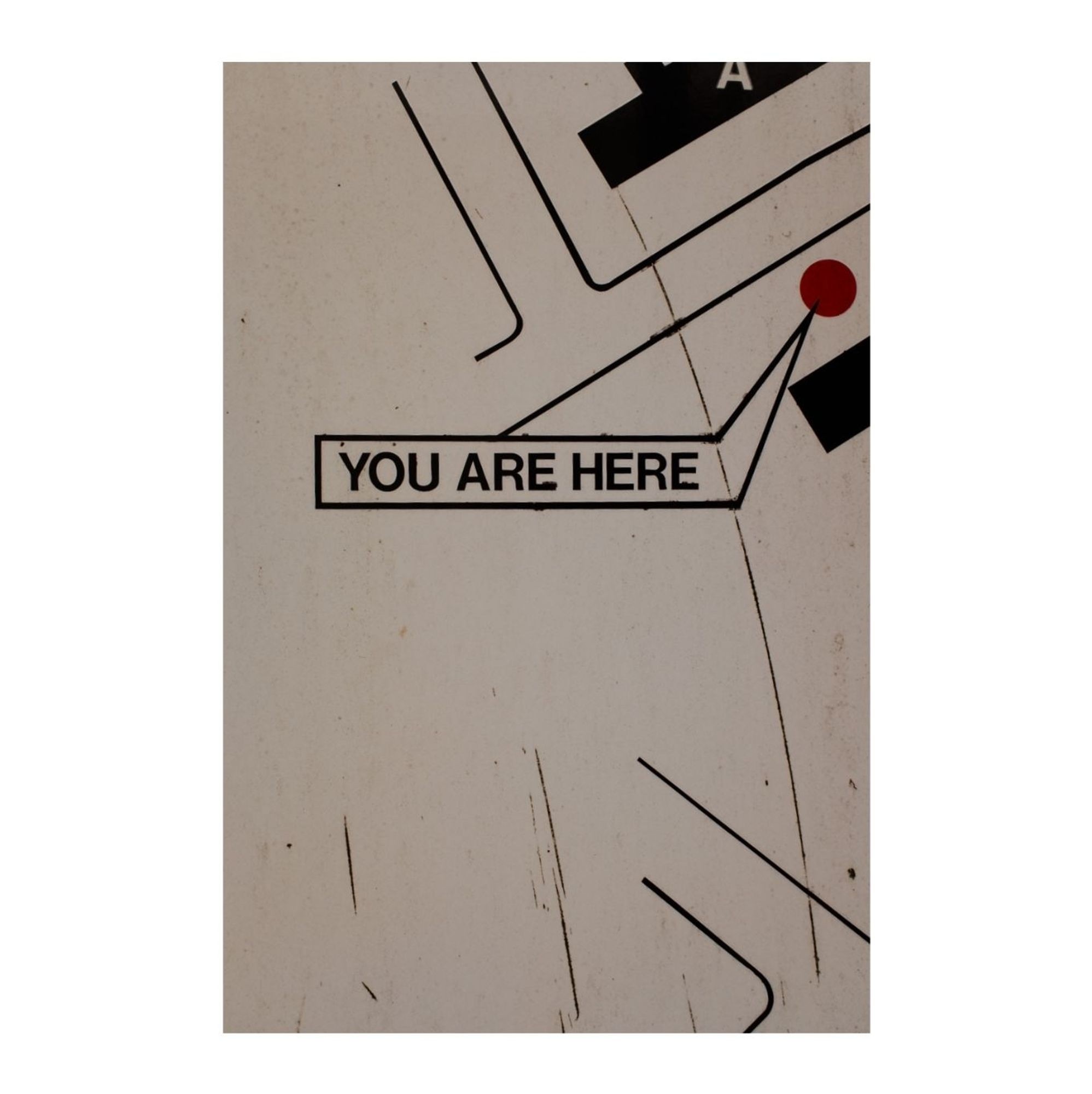 A You Are Here wayfinding sign with an arrow pointing to a red dot in a blankish space, nowhere.