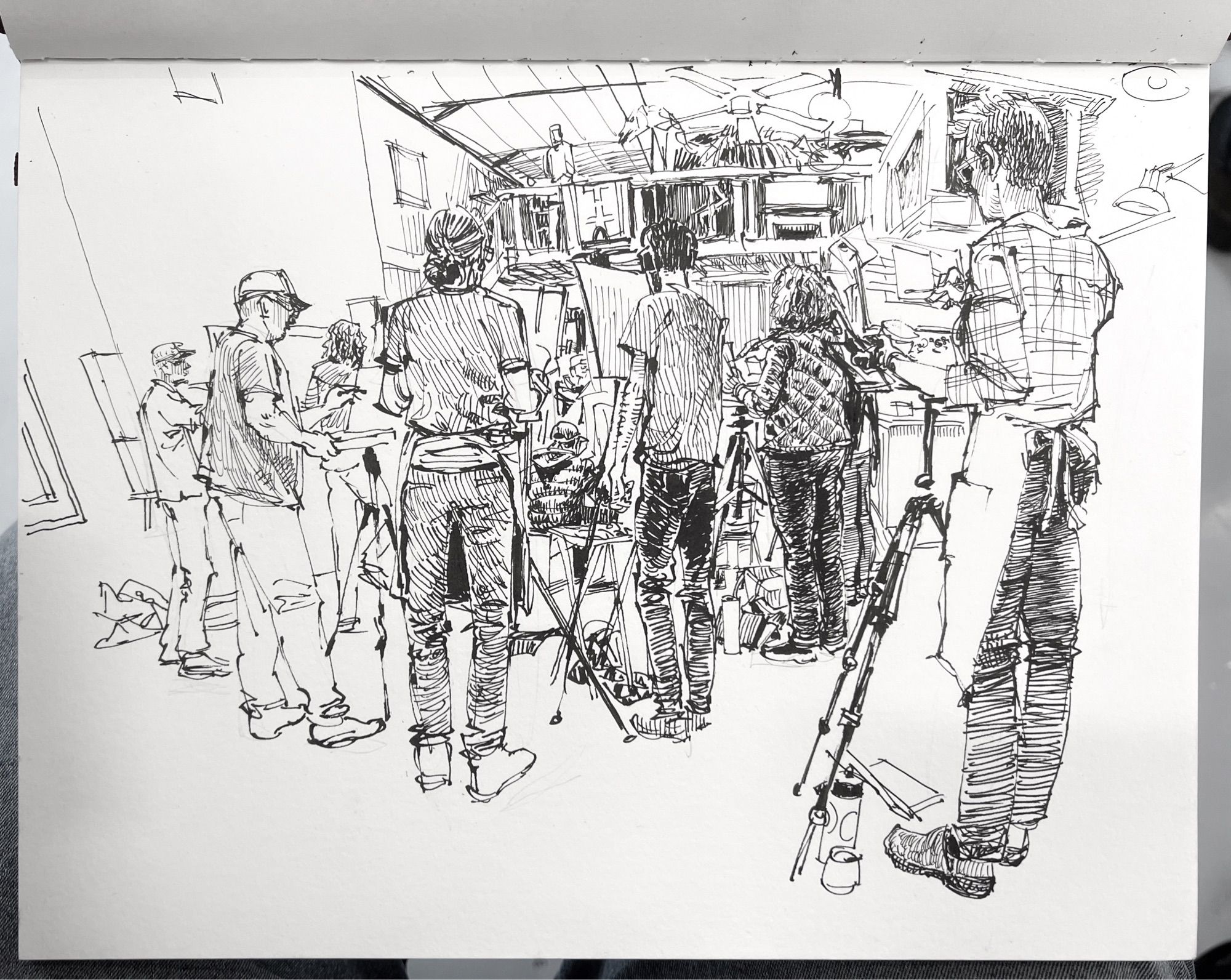 pen and ink drawing of a figure drawing sessions in an art studio multiple standing artists seen from behind, obscuring the figure