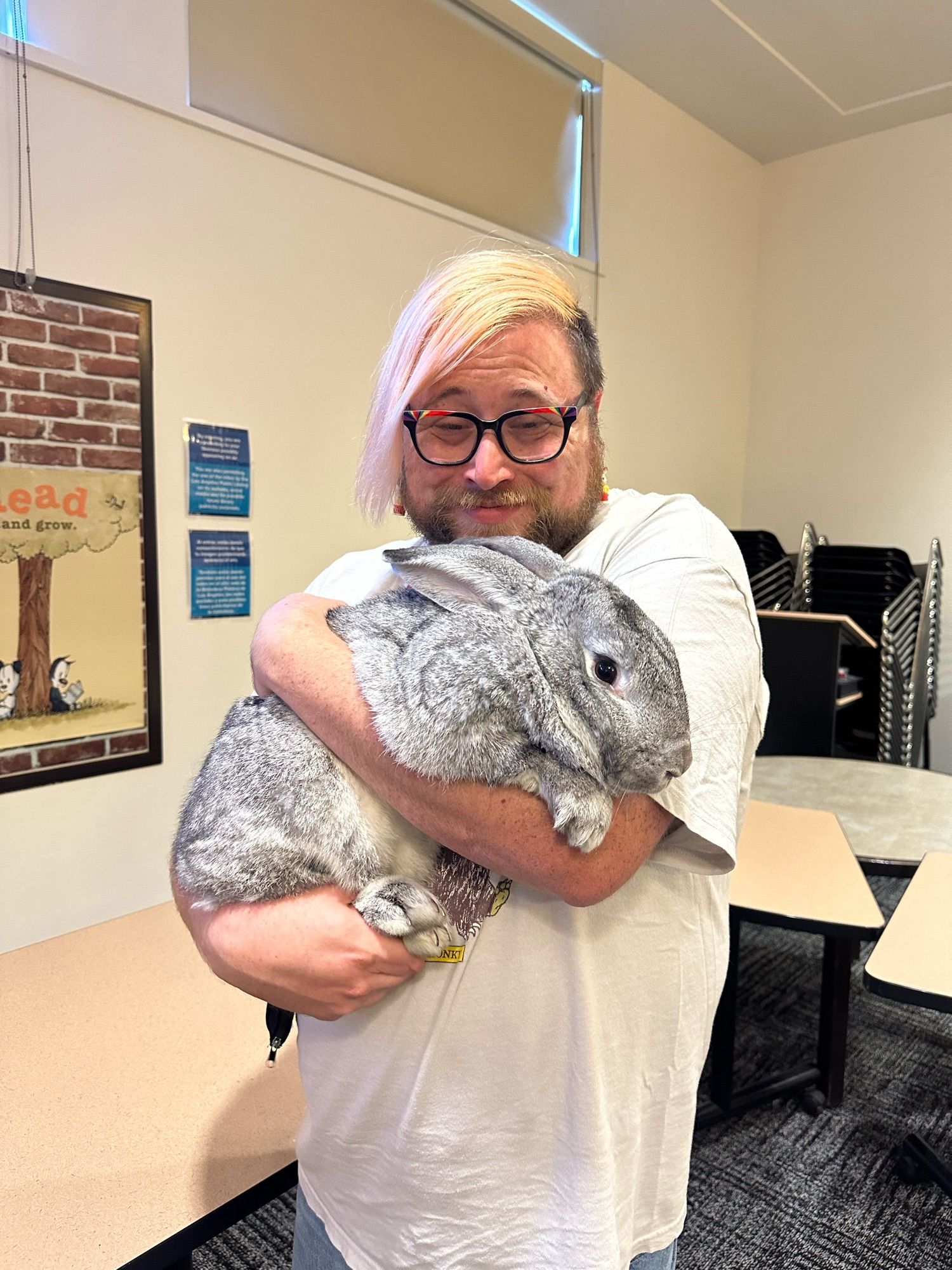 Vincey, crying with joy as they hold a silver colored Flemish Giant rabbit like it’s a baby.