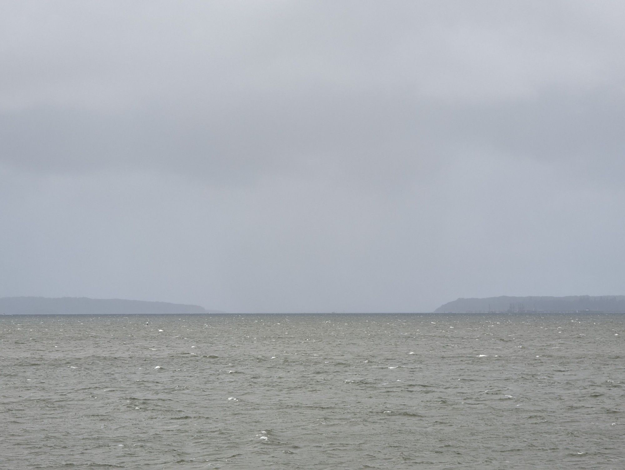 Deep hanging rain clouds over a bay harbour opening