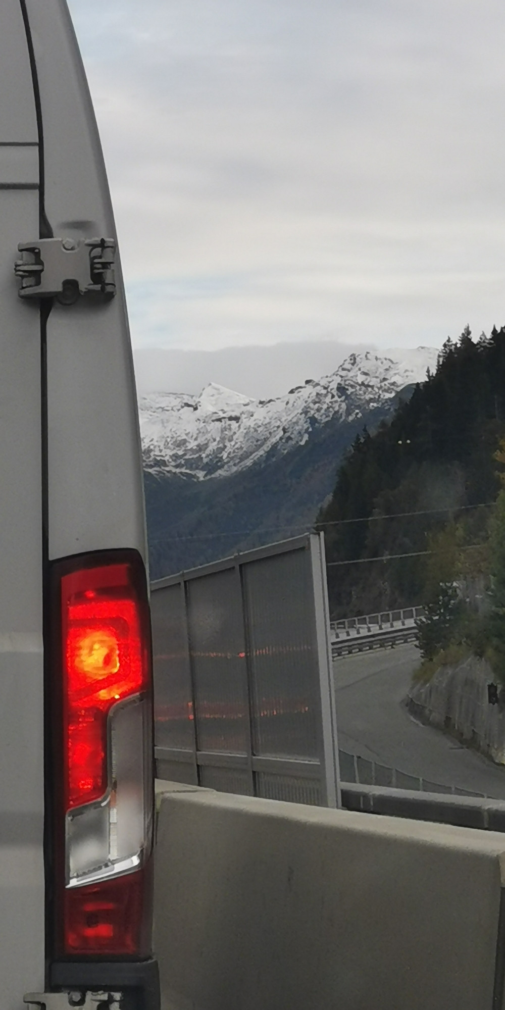 Rücklicht eines weißen Transporters, im Hintergrund Berge...