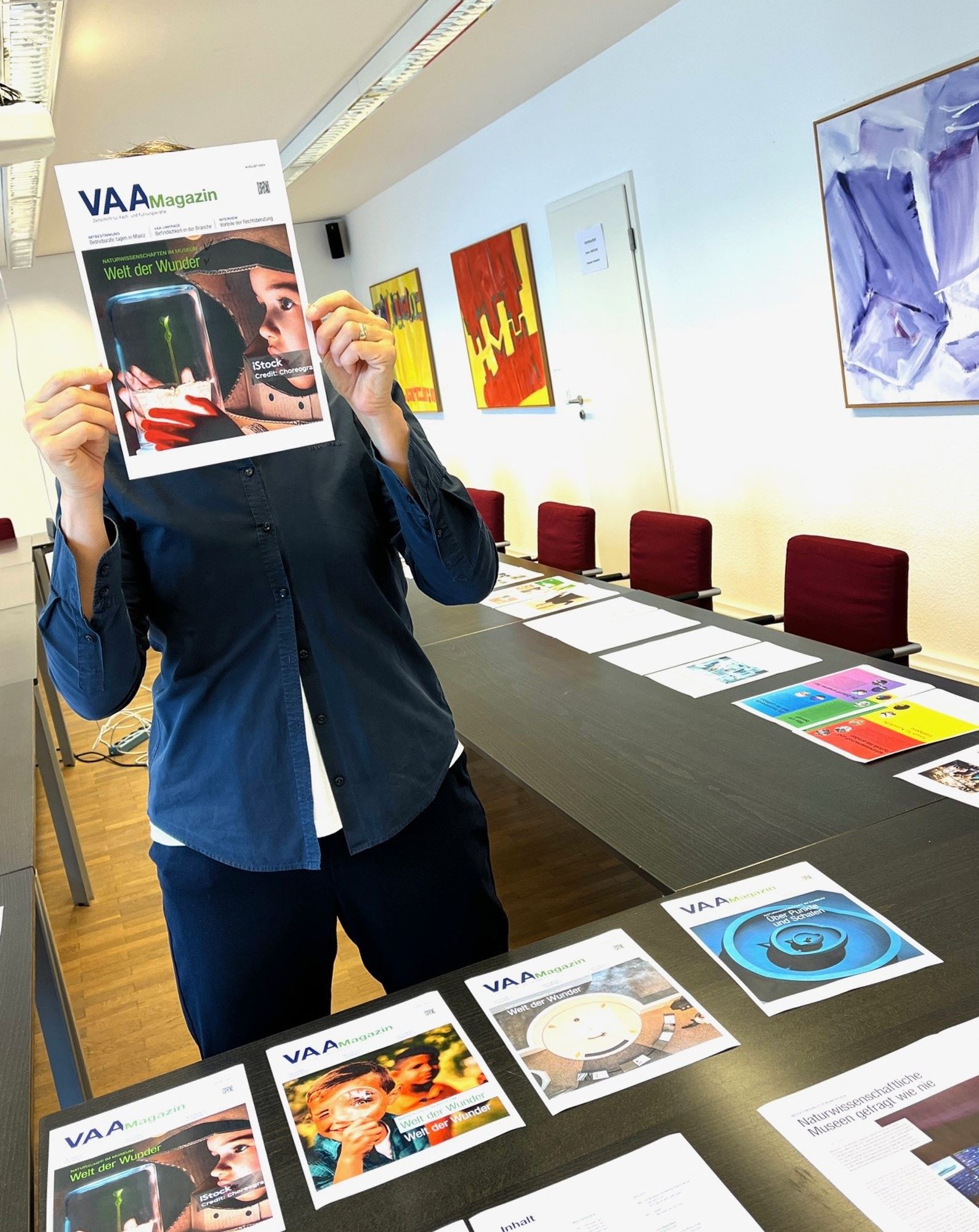 Bildredakteurin Simone Leuschner mit dem Cover des neuen VAA Magazins vor dem Kopf. Foto: VAA.